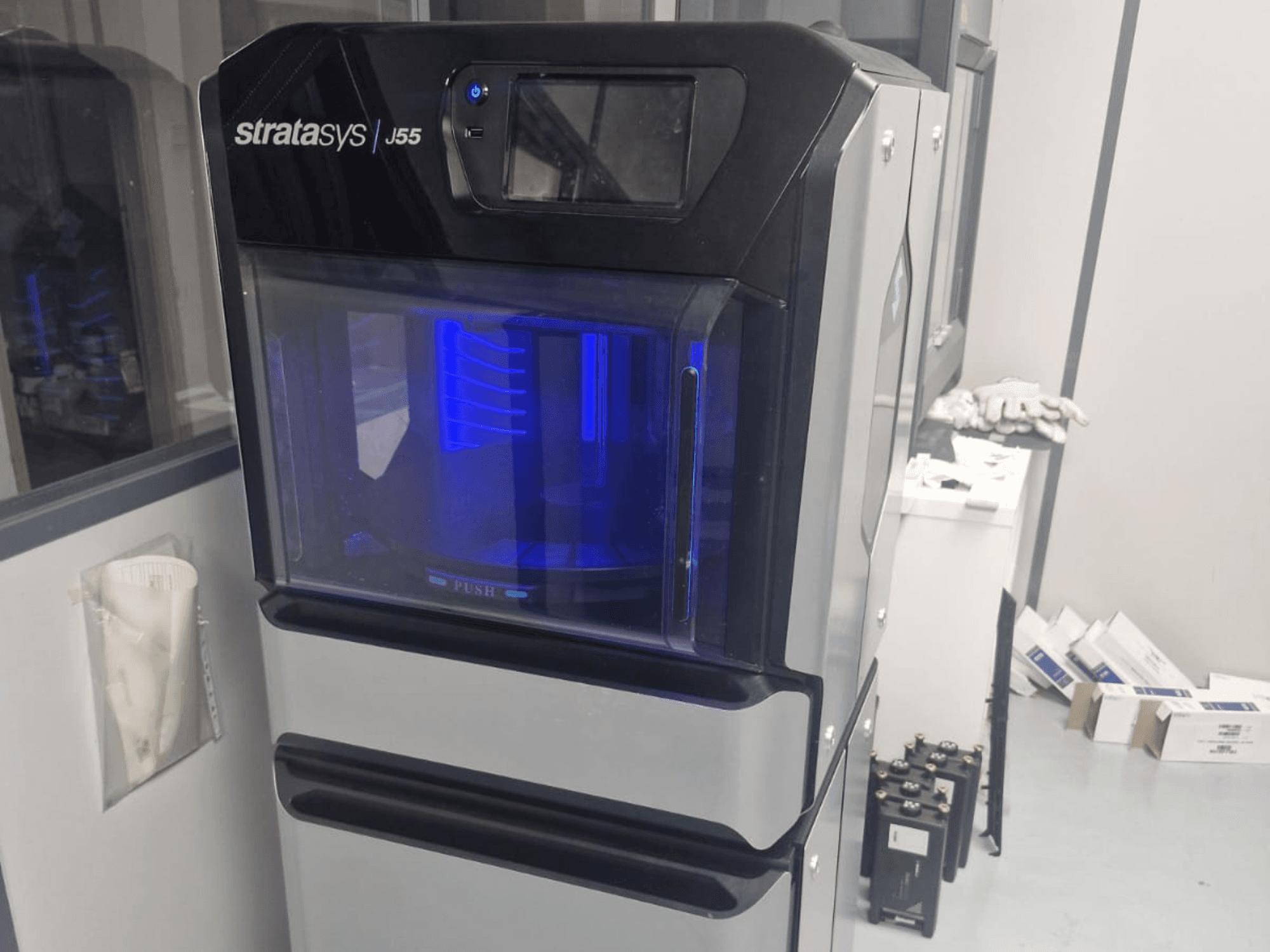 Stratasys J55 Prime plastik 3D yazıcı, şık tasarımını ve aydınlatılmış baskı alanını sergileyen yandan görünümde.