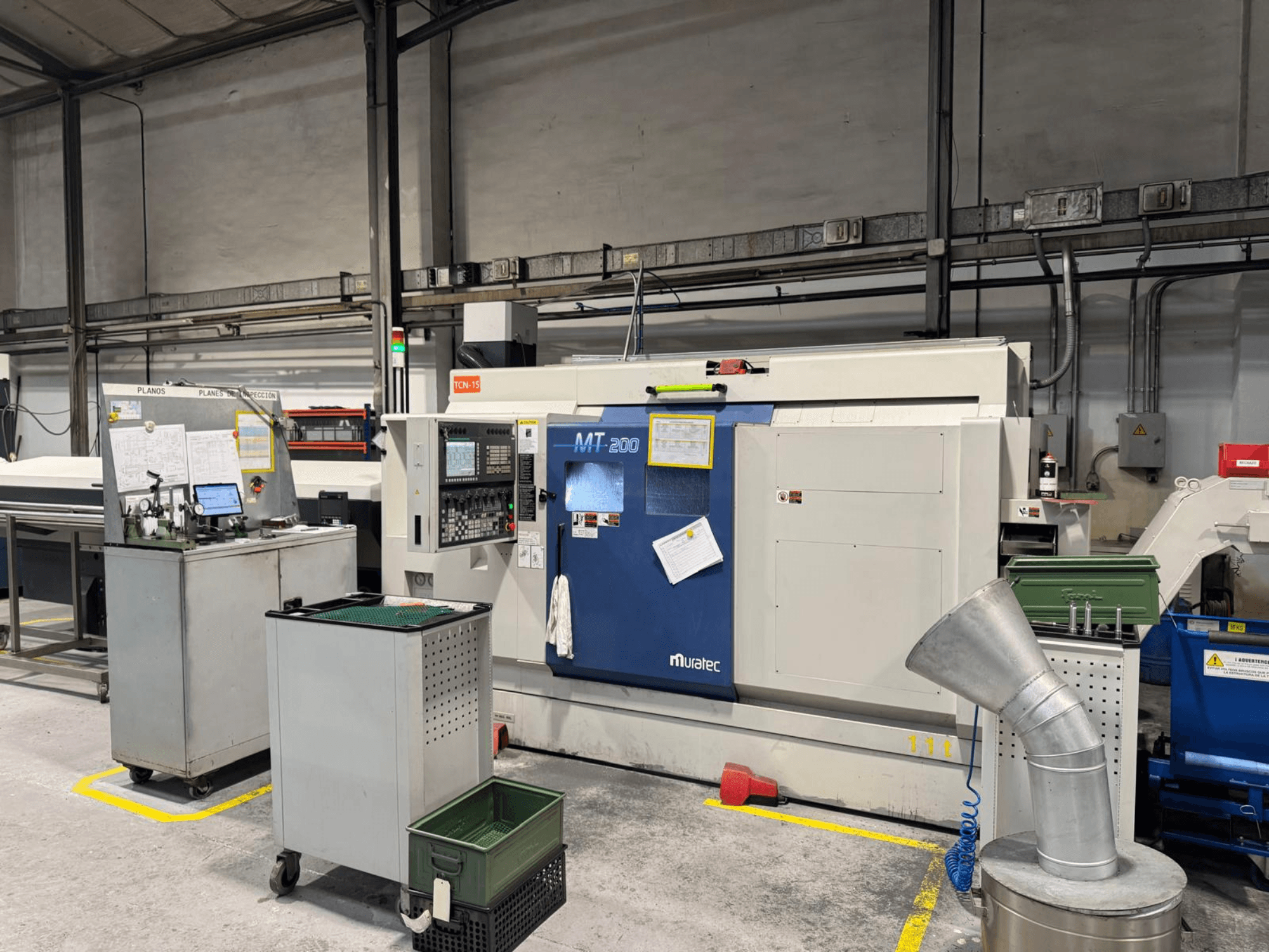 Muratec MT200 çok milli torna makinesi fabrika ortamında, önden bakıldığında kontrol paneli ve çevresindeki ekipmanlarla birlikte.