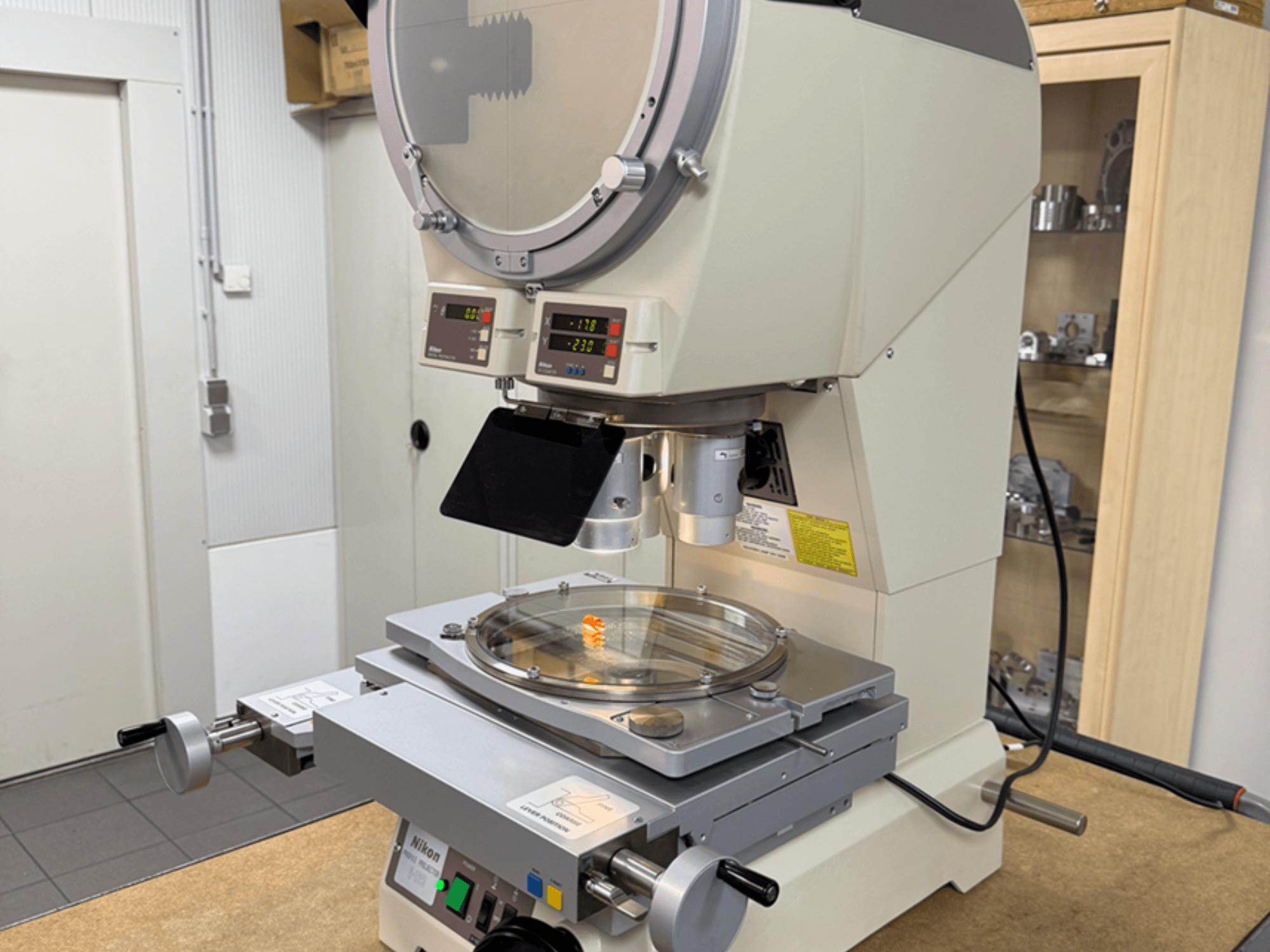 Önden görünümlü Nikon model mikroskop, dijital ekranlar, ayarlanabilir bir sahne ve dairesel bir cam plaka içerir.