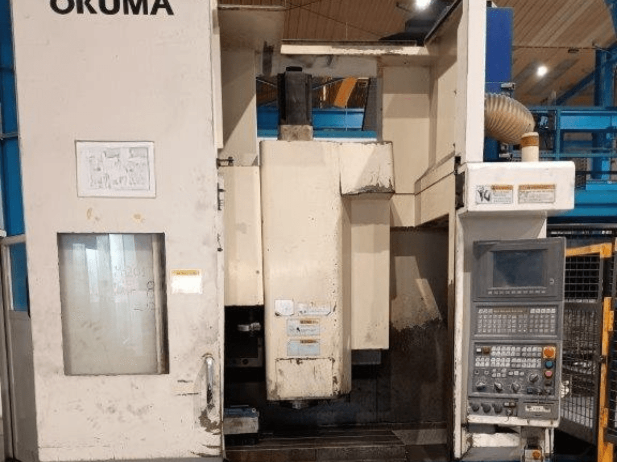 Okuma CNC freze makinesi, önden görünüm, düğmeli kontrol paneli, ekran ve makine gövdesi üzerinde görünür işaretler.