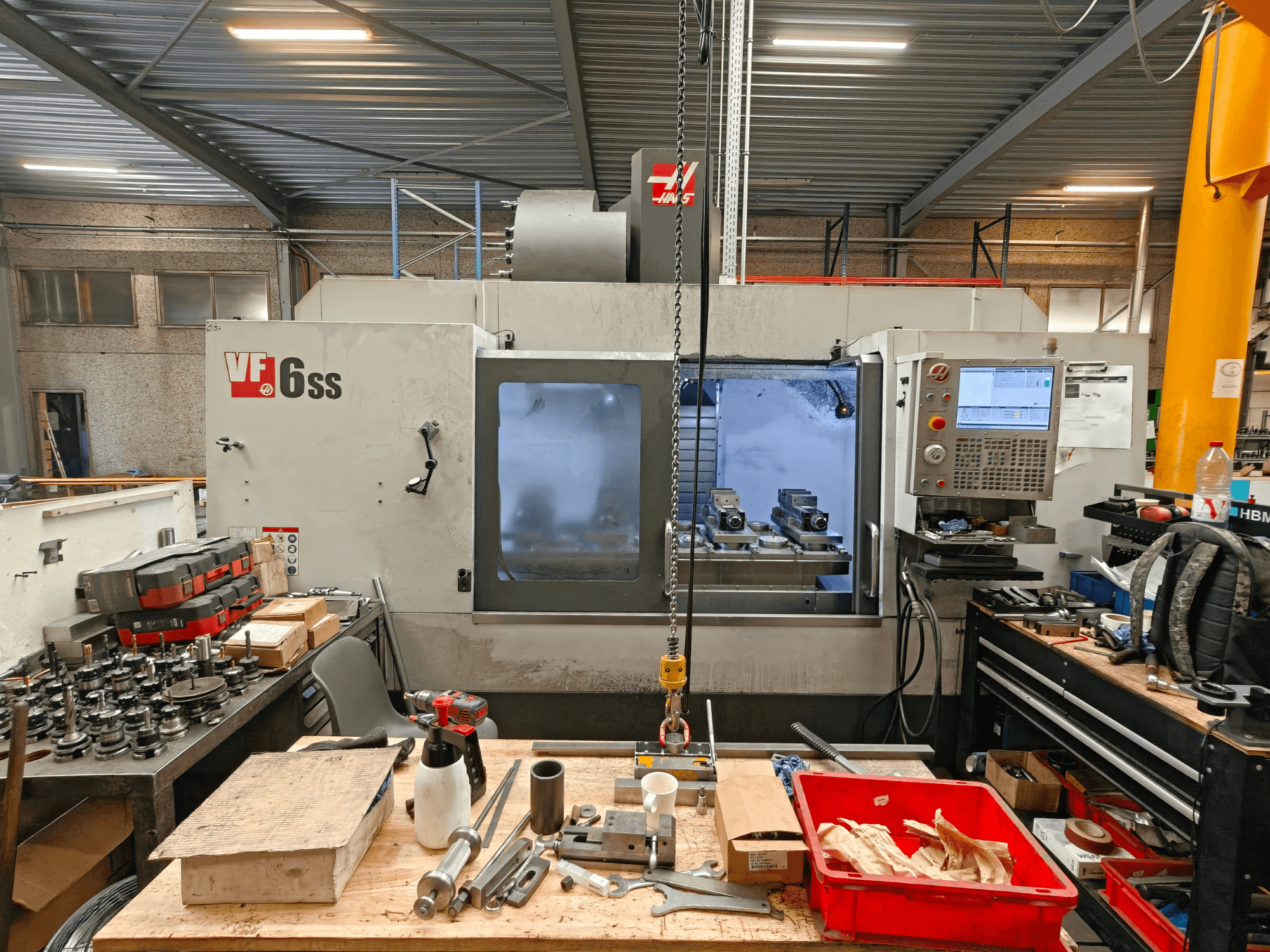 Bir atölyede bulunan Haas VF-6SS dikey işleme merkezi; kontrol paneli ve aletlerle dolu çalışma alanını gösteren yandan görünüm.