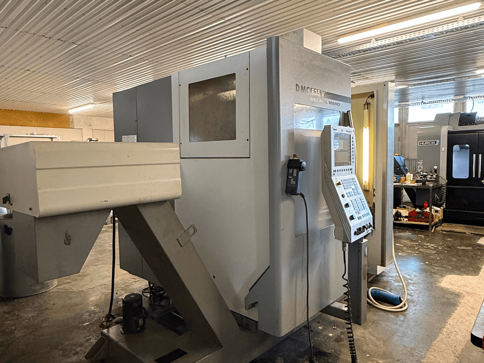 Atölyede DMC G635V freze makinesi, kontrol paneli ve bağlı elektrikli aletler görünür şekilde önden görünüm.