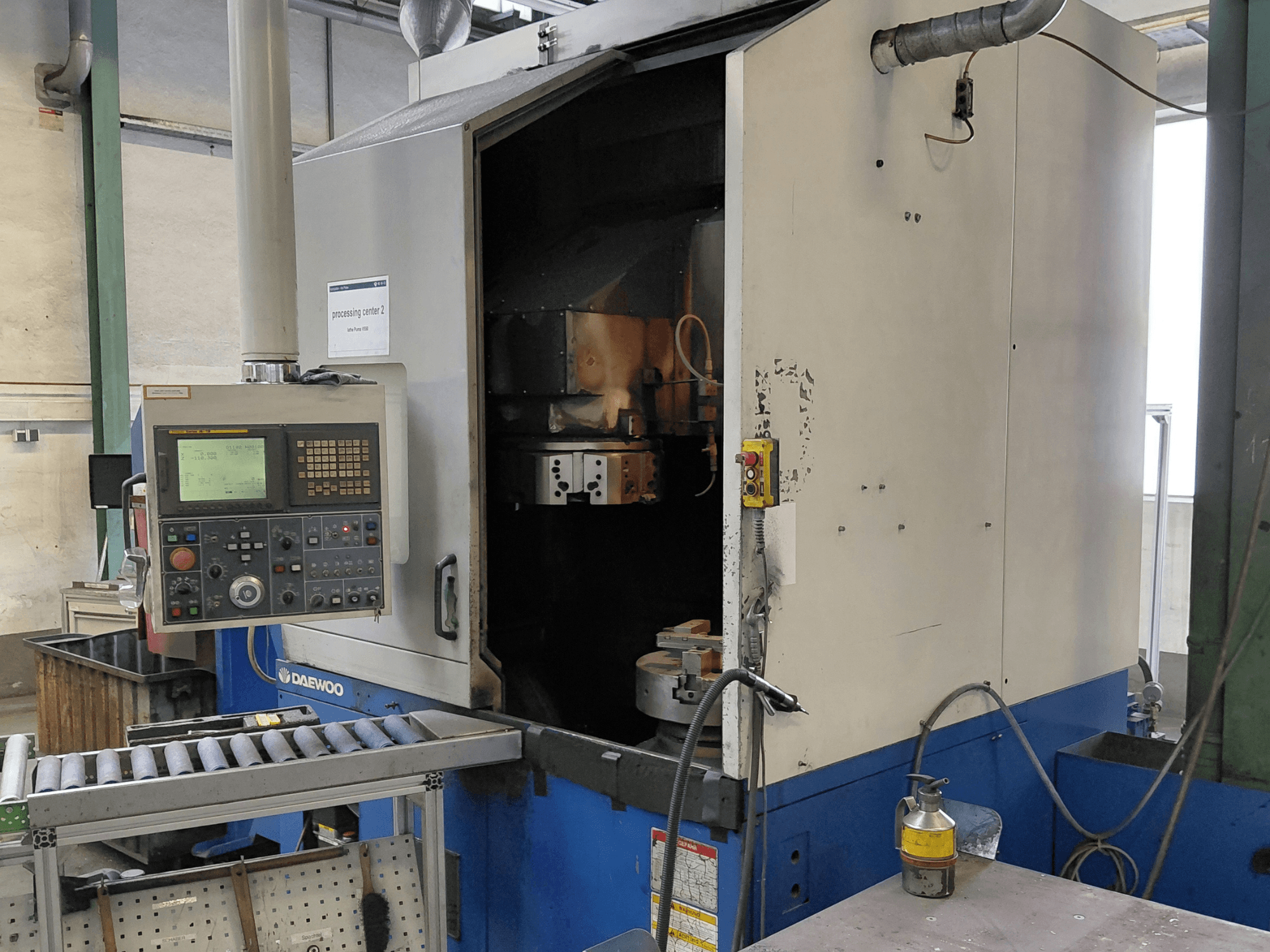 Daewoo Puma V550 dikey tornalama makinesi, kontrol paneli, iş mili ve soğutma sıvısı bağlantısını gösteren önden görünüm.