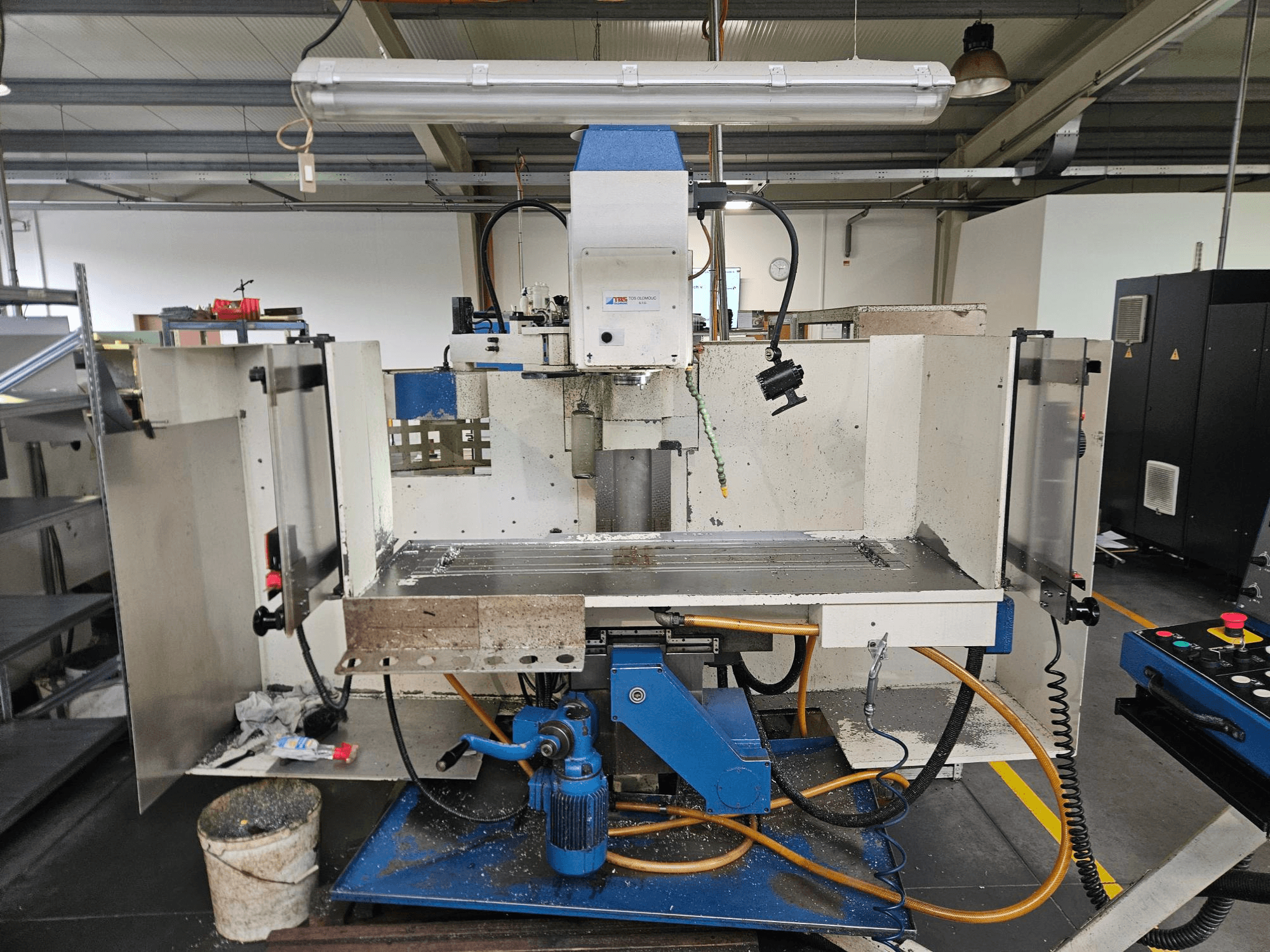 TOS Olomouc FV30 CNC Bir atölyede dikey işleme merkezi, kontrol panelini, çalışma tezgahını ve soğutma sistemini gösteren önden görünüm.