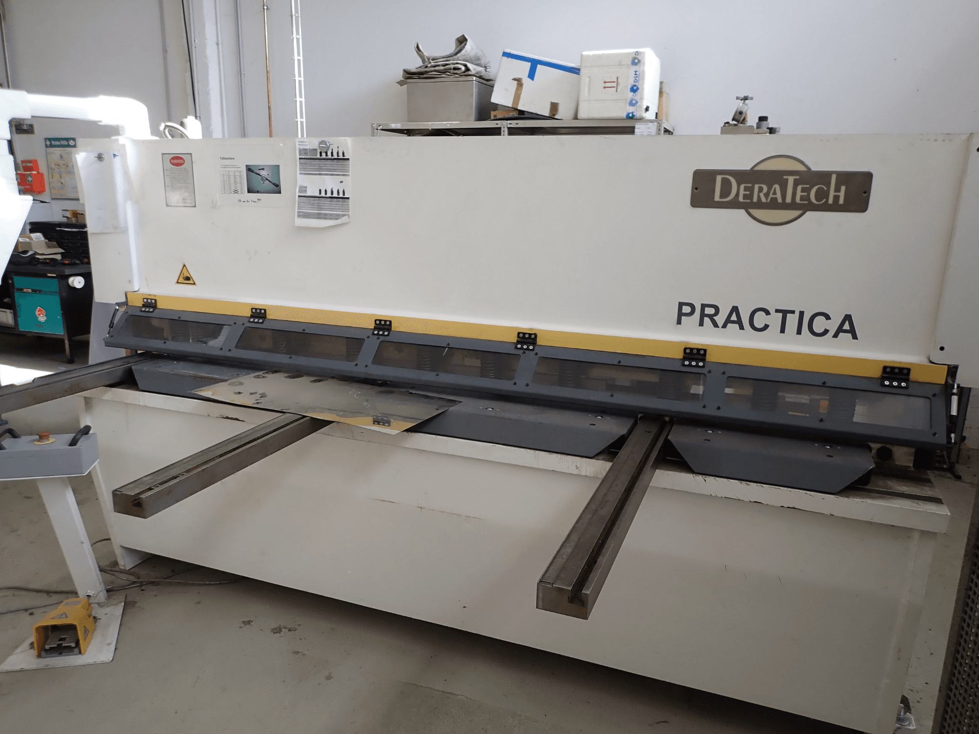 DERATECH Practica CNC kesme makinesi, önden görünüm, kesme bıçağını ve çalışma yüzeyindeki metal levhaları gösterir.