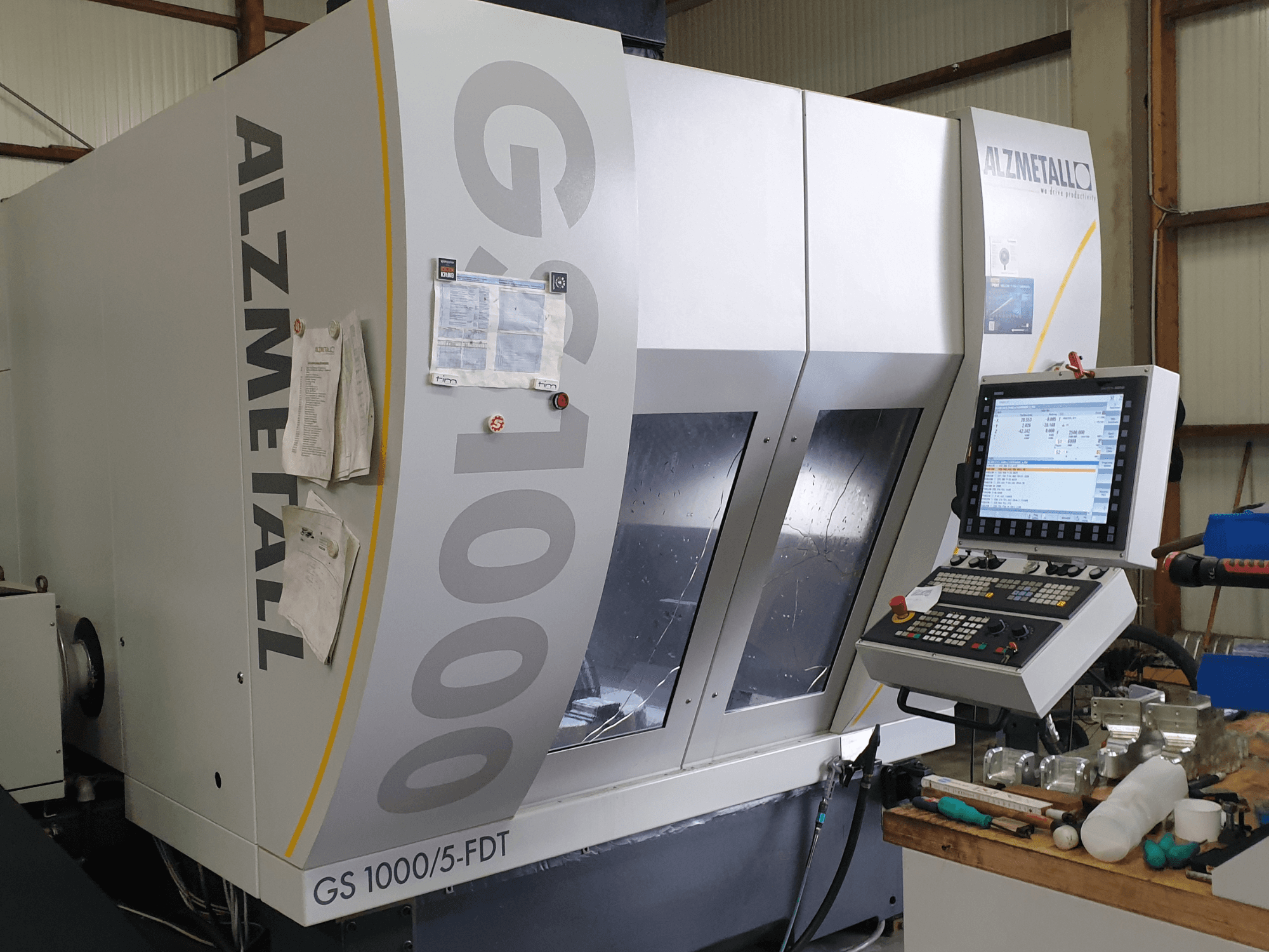 Alzmetall GS 1000/5-FDT dikey işleme merkezinin önden görünümü; kontrol paneli ve çalışma alanı görülüyor.