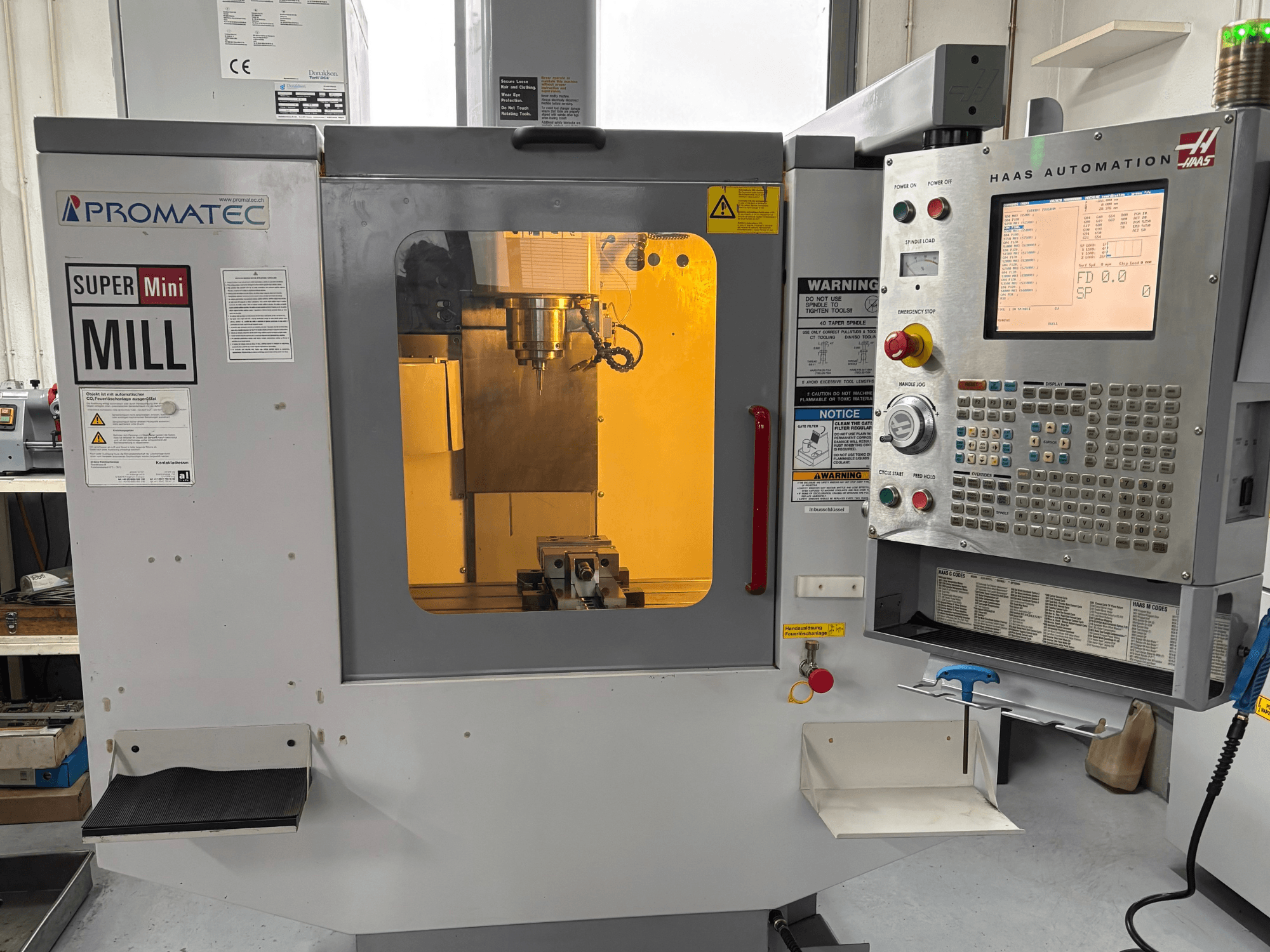 Promatec Super Mini Mill önden görünümde, Haas Automation kontrol paneli ve içinde görünür kesme takımı ile donatılmıştır.