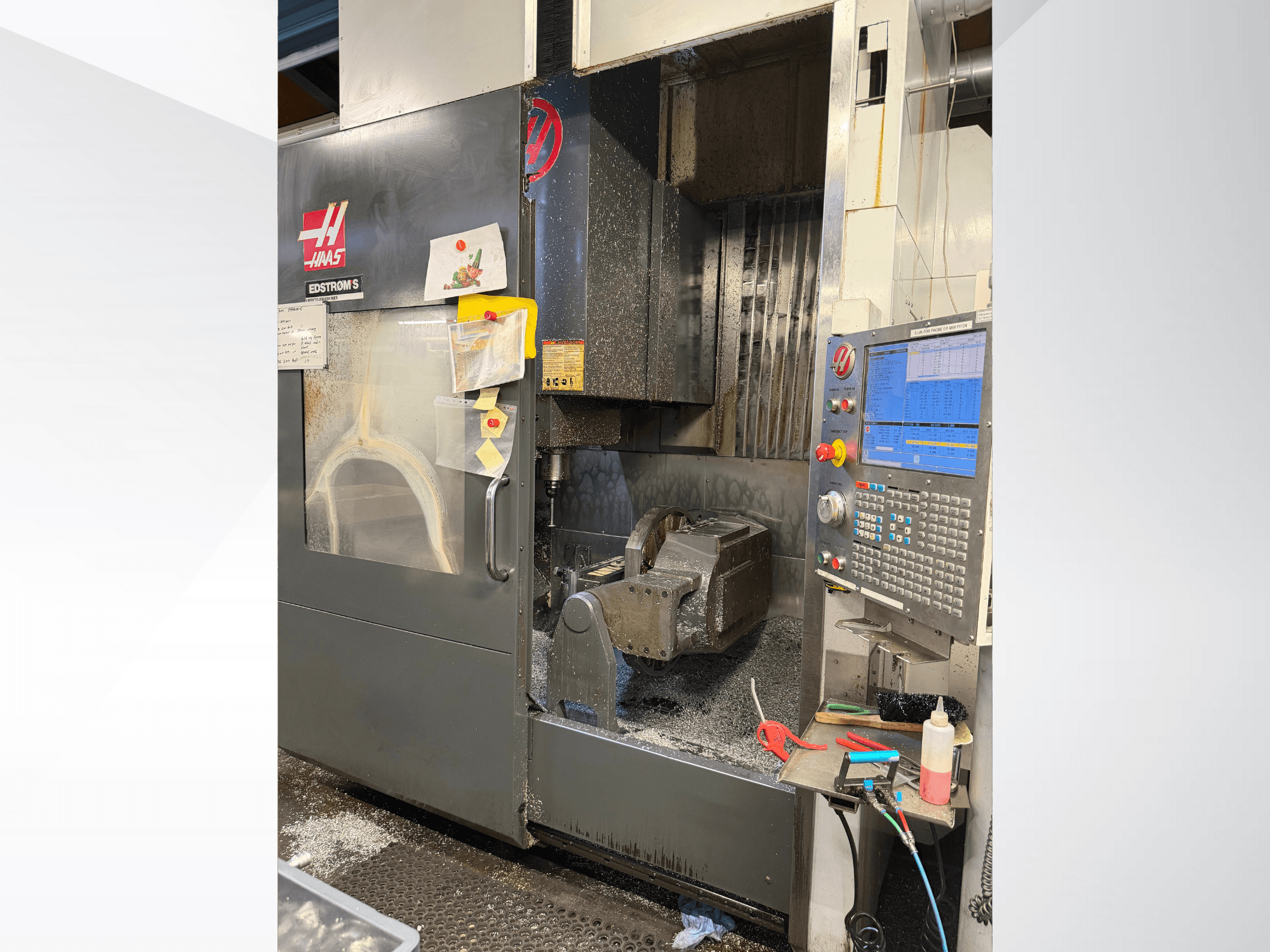 Haas CNC makine modeli EDSTROM S, önden görünüm, metal iş parçasını, kontrol panelini ve içindeki metal talaşlarını gösterir.
