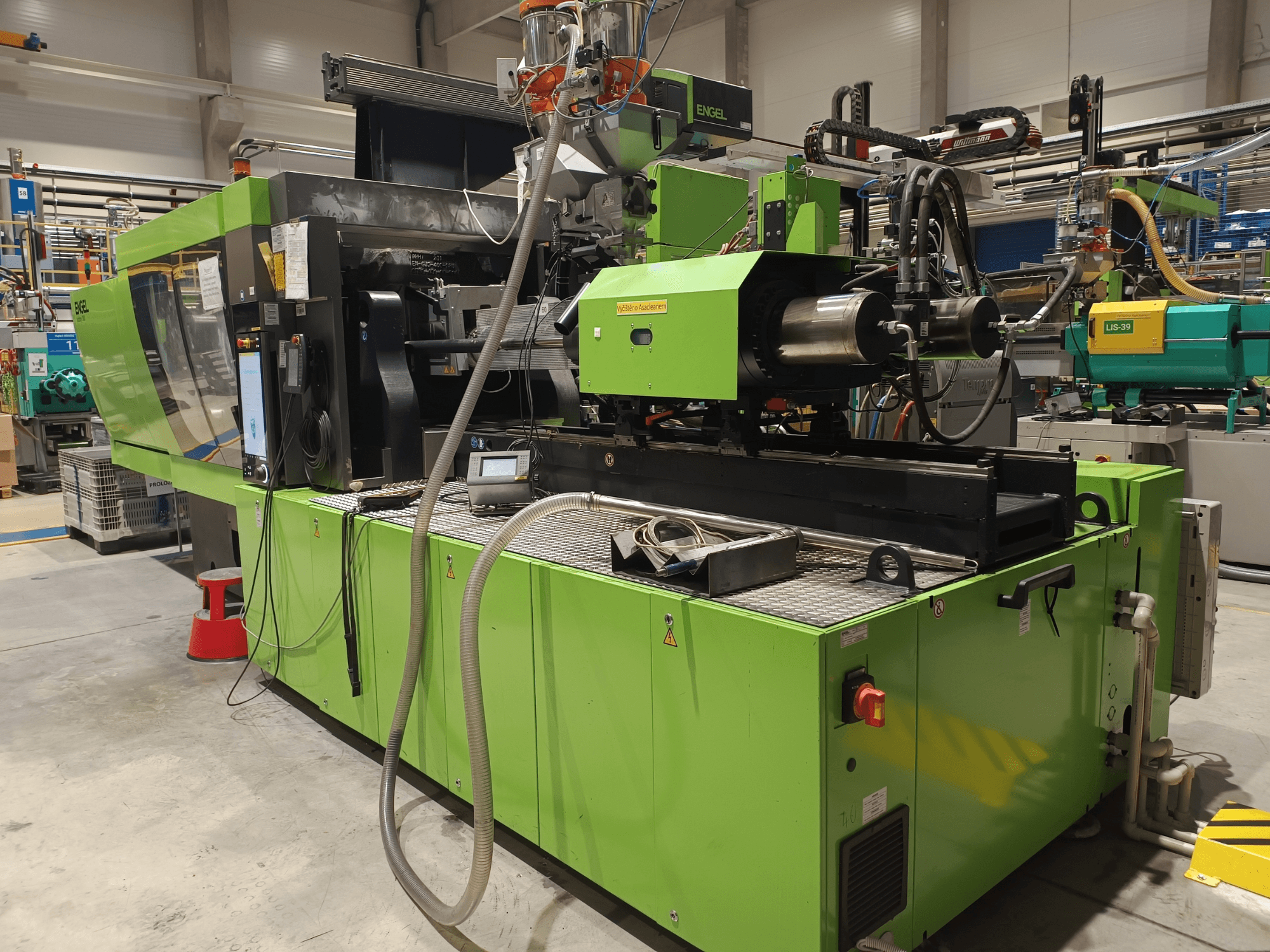 Engel enjeksiyon kalıplama makinesi, yandan görünüm, yeşil dış yüzey, dokunmatik ekran paneli ve hidrolik bileşenler görünür.