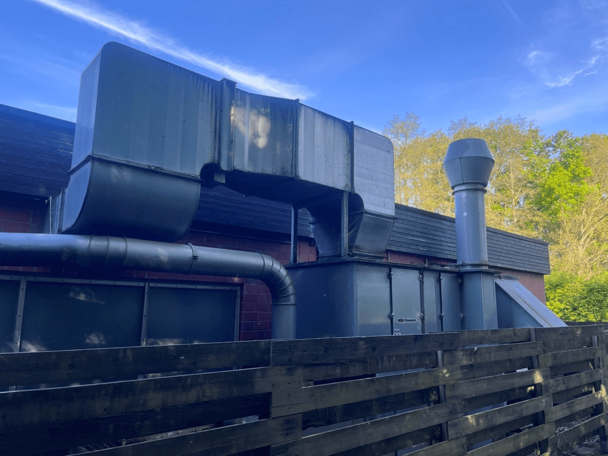 Metalik kanallı endüstriyel havalandırma sistemi, yandan görünüm; kare ve silindirik bir baca içerir, yeşil kaplama.