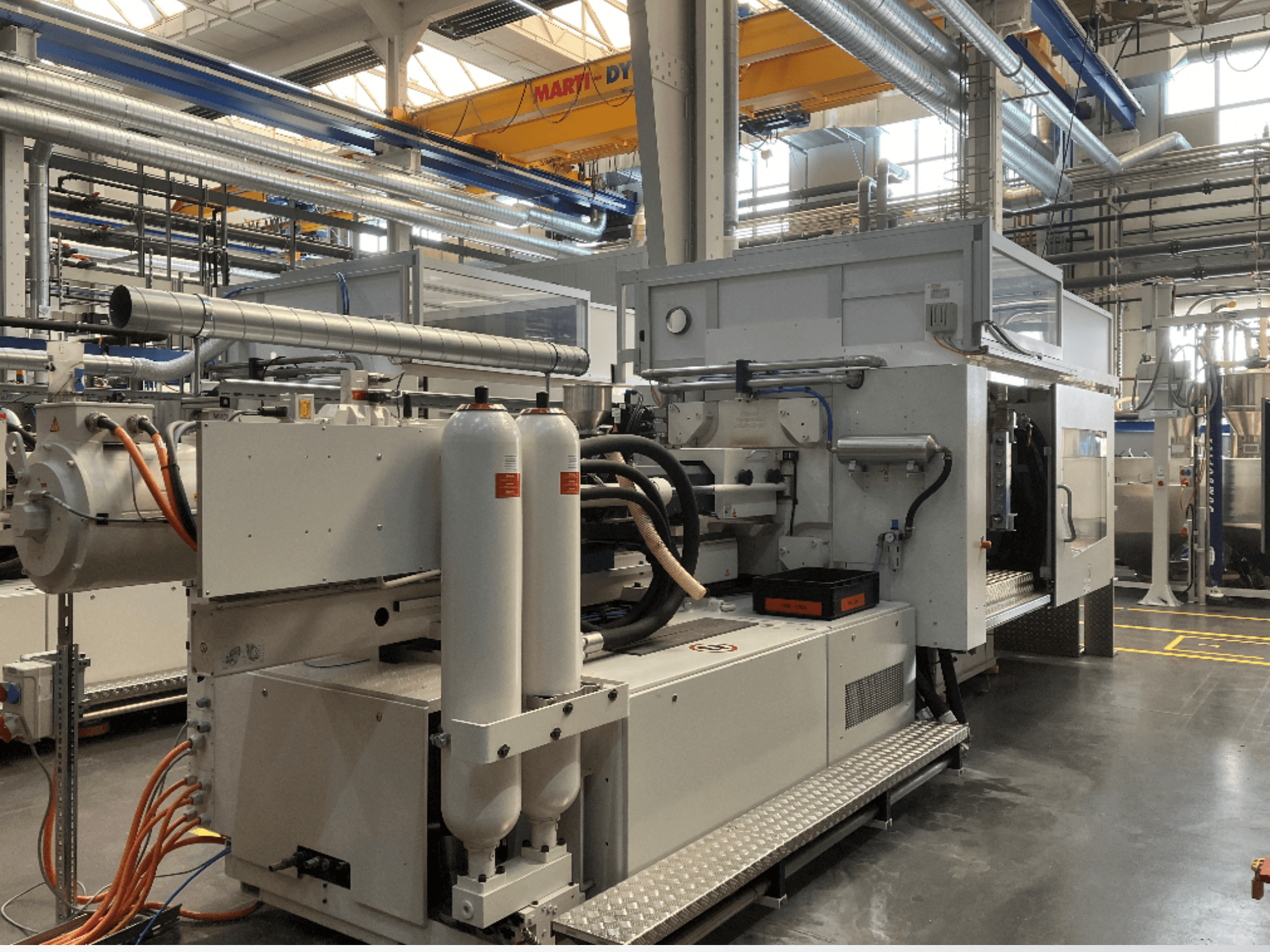 Birden fazla hortum, iki dikey tank ve kontrol paneli ile yandan görünümde gösterilen endüstriyel makine; marka/model görünmüyor.