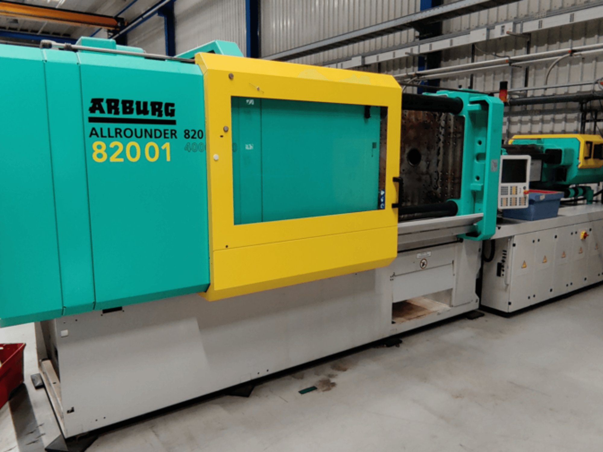 Arburg ALLROUNDER 82001 deniz mavisi ve sarı renkli enjeksiyon kalıplama makinesi, kontrol panelini ve çalışma özelliklerini gösteren yandan görünüm.