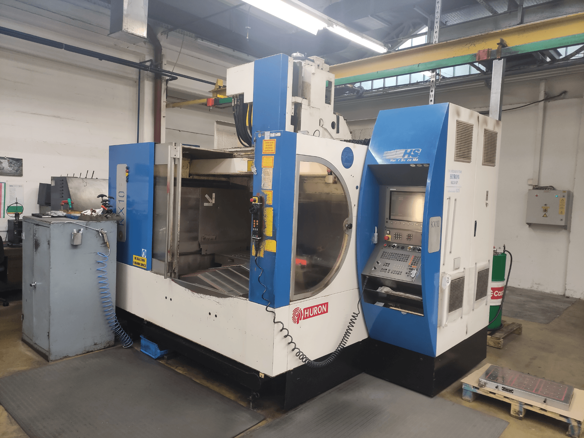 Bir atölyede HURON KX10 CNC makinesi, önden görünüm, kontrol paneli ve işleme için geniş açıklık.