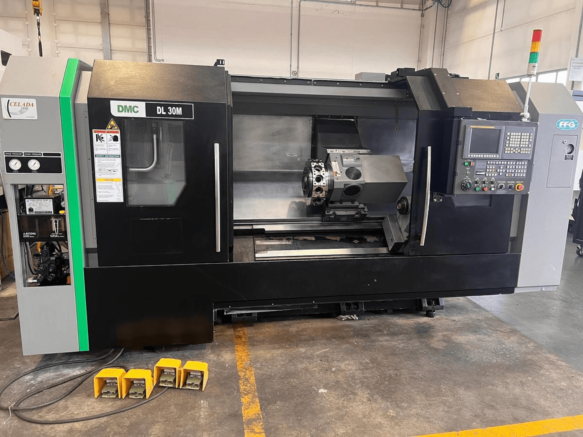 DMC DL 30M CNC makinesi, kontrolleri, iş milini ve zemindeki üç ayak pedalını gösteren yandan görünüm.