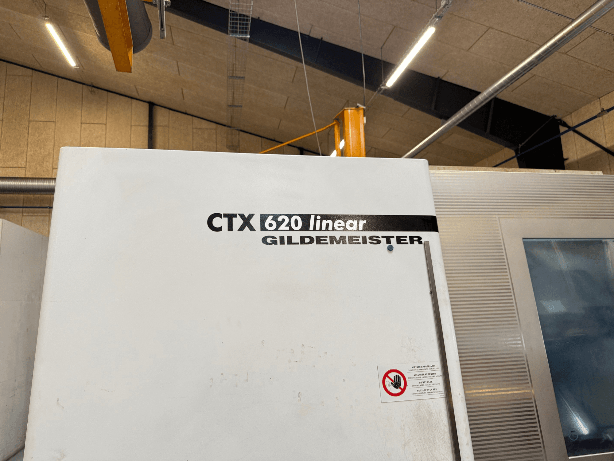 CTX 620 Lineer Gildemeister makinesi yandan görünüm, beyaz dış yüzey ve güvenlik uyarı etiketleri.