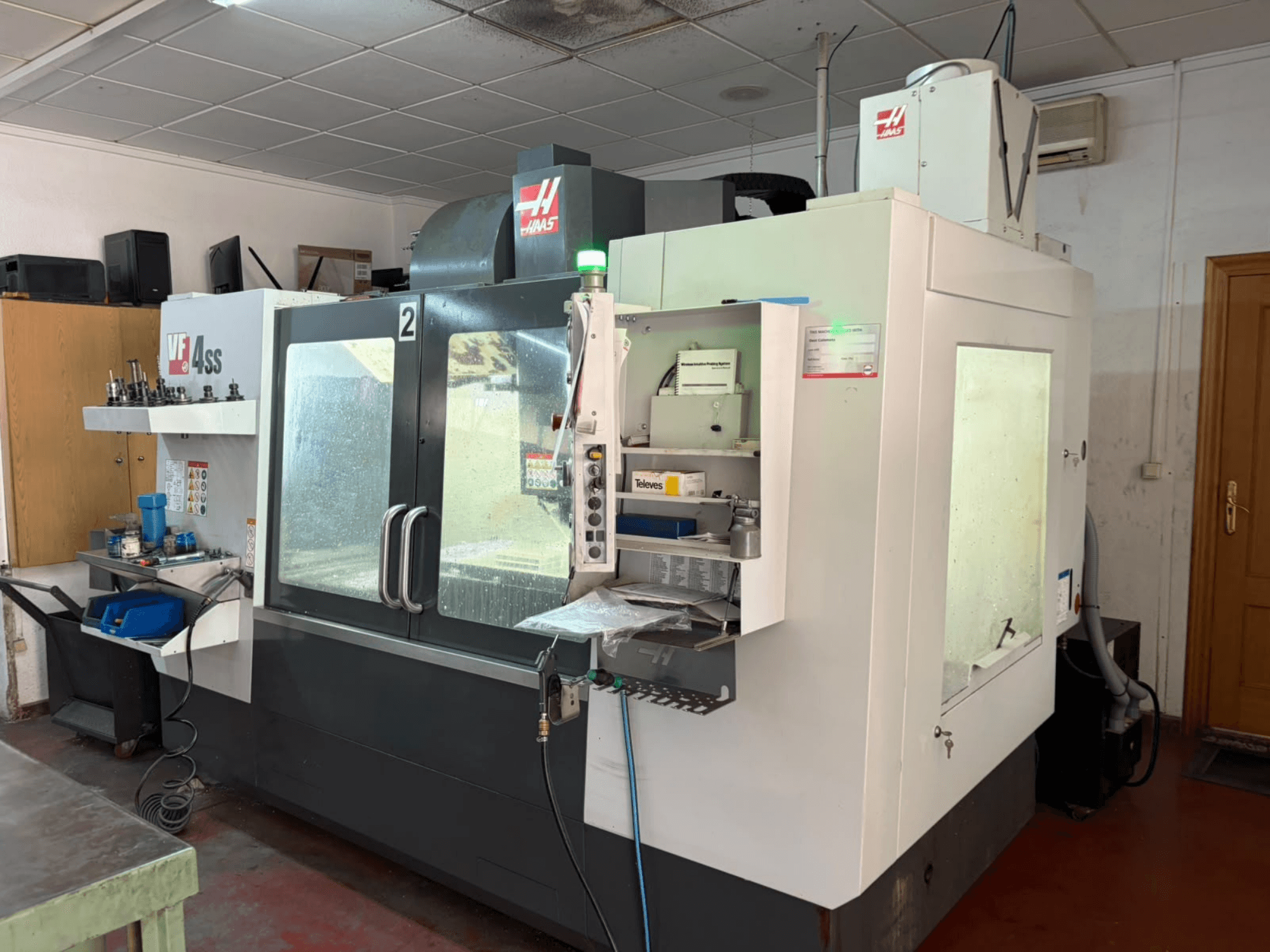 Bir atölyede bulunan HAAS VF 4SS dikey işleme merkezi; önden görünüm; kontrol paneli ile alet ve malzemelerin bulunduğu çalışma alanı görülüyor.
