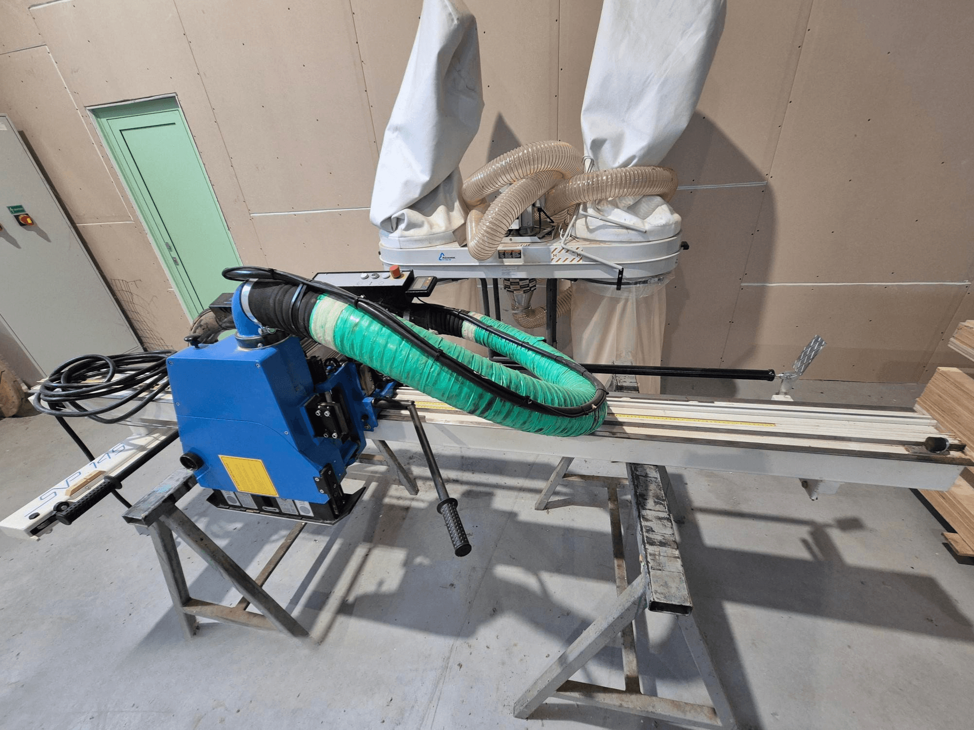 Yeşil toz hortumu ve desteğiyle mavi SVP-175 yatay panel testere, atölye ortamında yandan görünüm.