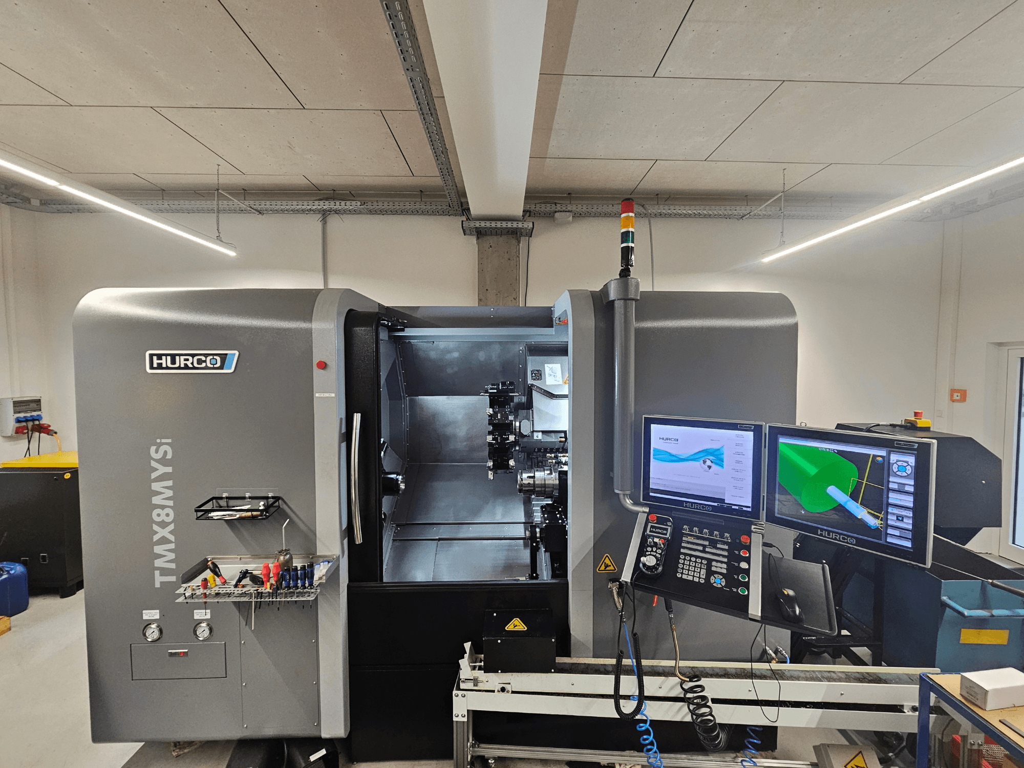 Hurco TMX 8 MYSi torna freze merkezi bir atölyede, çift monitör, kontrol paneli ve yan tarafta aletler.