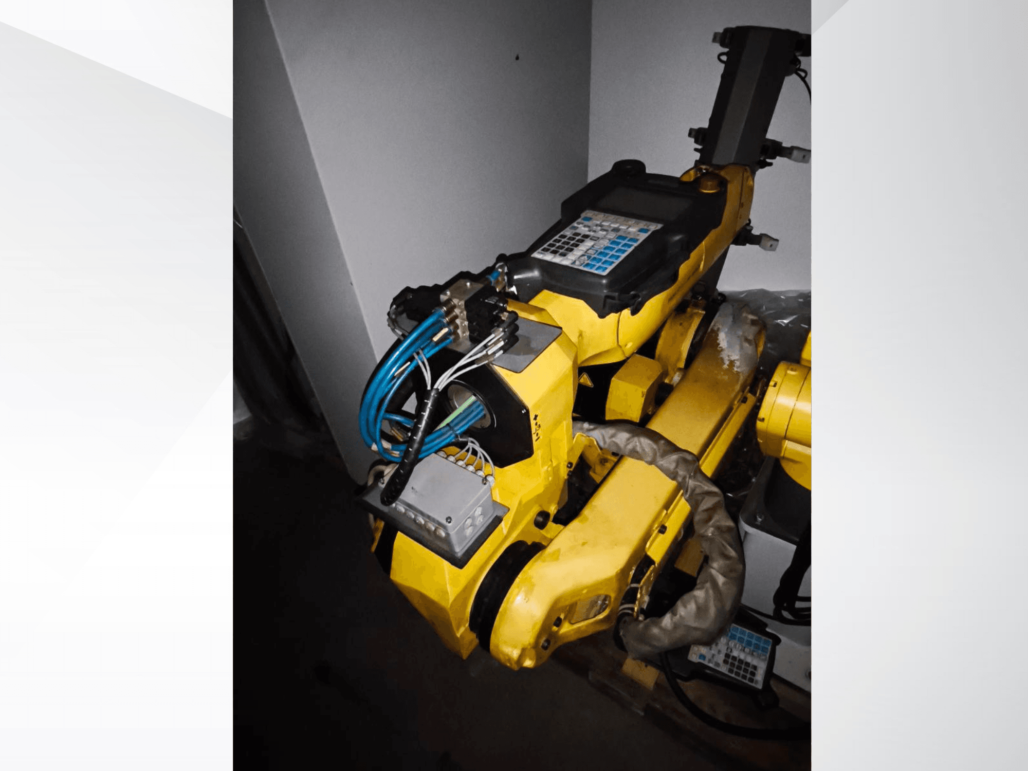FANUC M-20iA robot kolunun yandan görünümü, sarı gövdeyi, kontrol panelini ve bağlı kabloları gösterir.