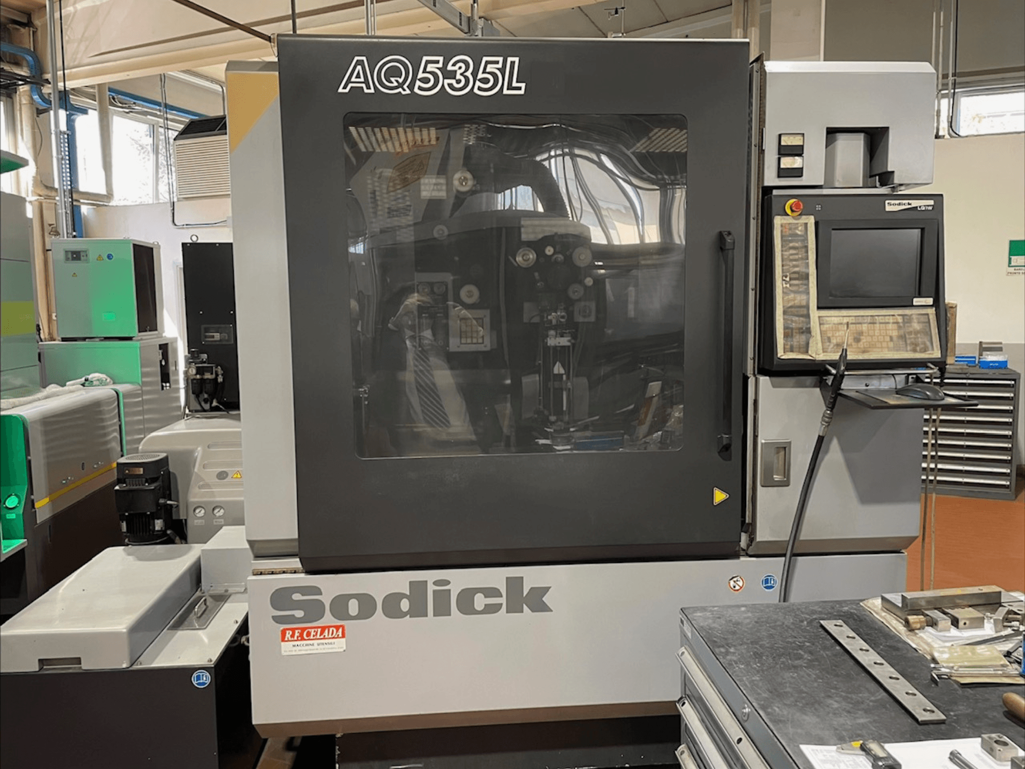 Sodick AQ535L Tel Erozyon makinesinin önden görünümü, kontrol paneli ve şeffaf koruyucu kapak.