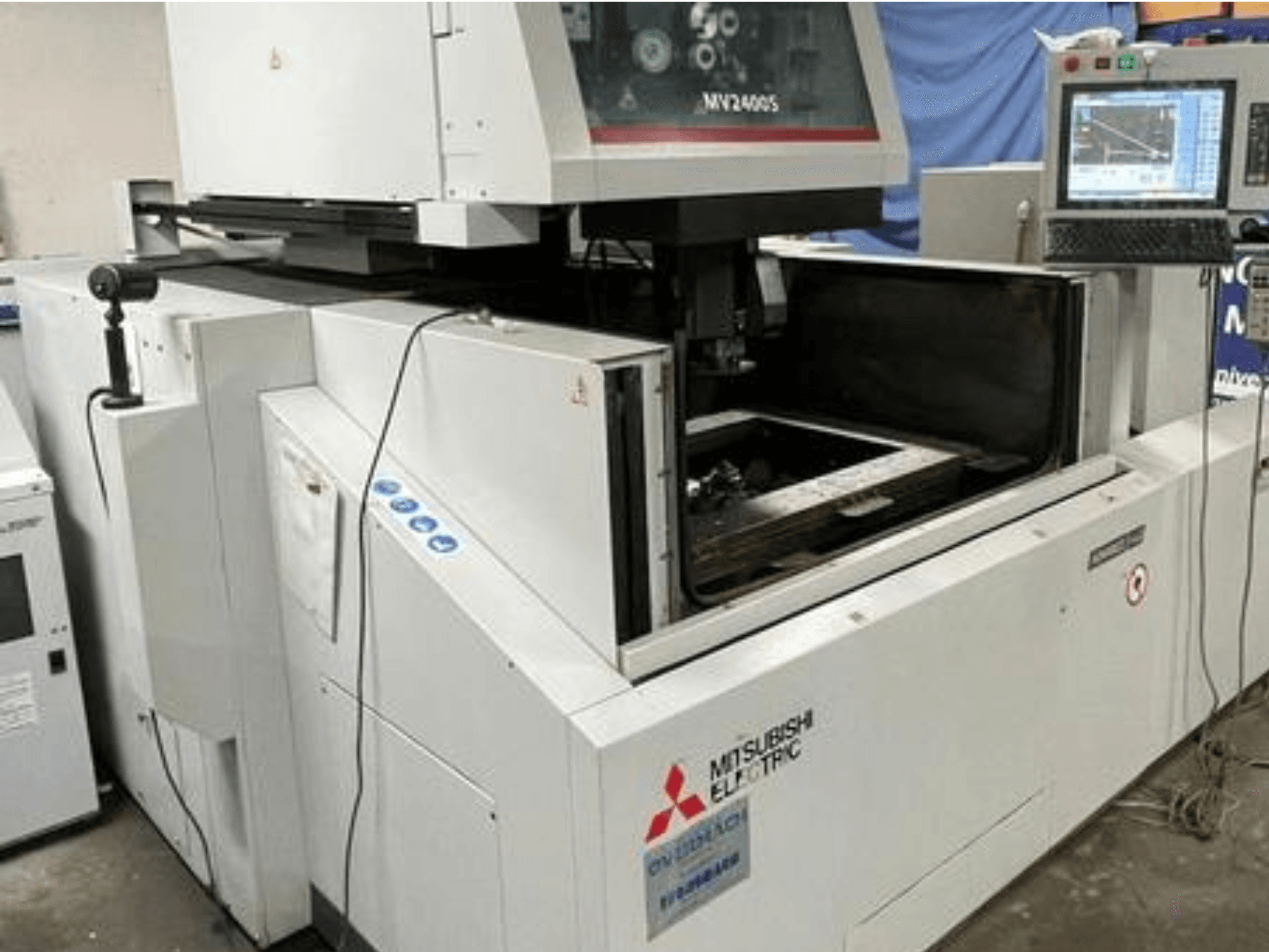 Mitsubishi Electric MV2400S tel kesme EDM makinesi, önden görünüm, kontrol panelini ve açık çalışma alanını gösterir.
