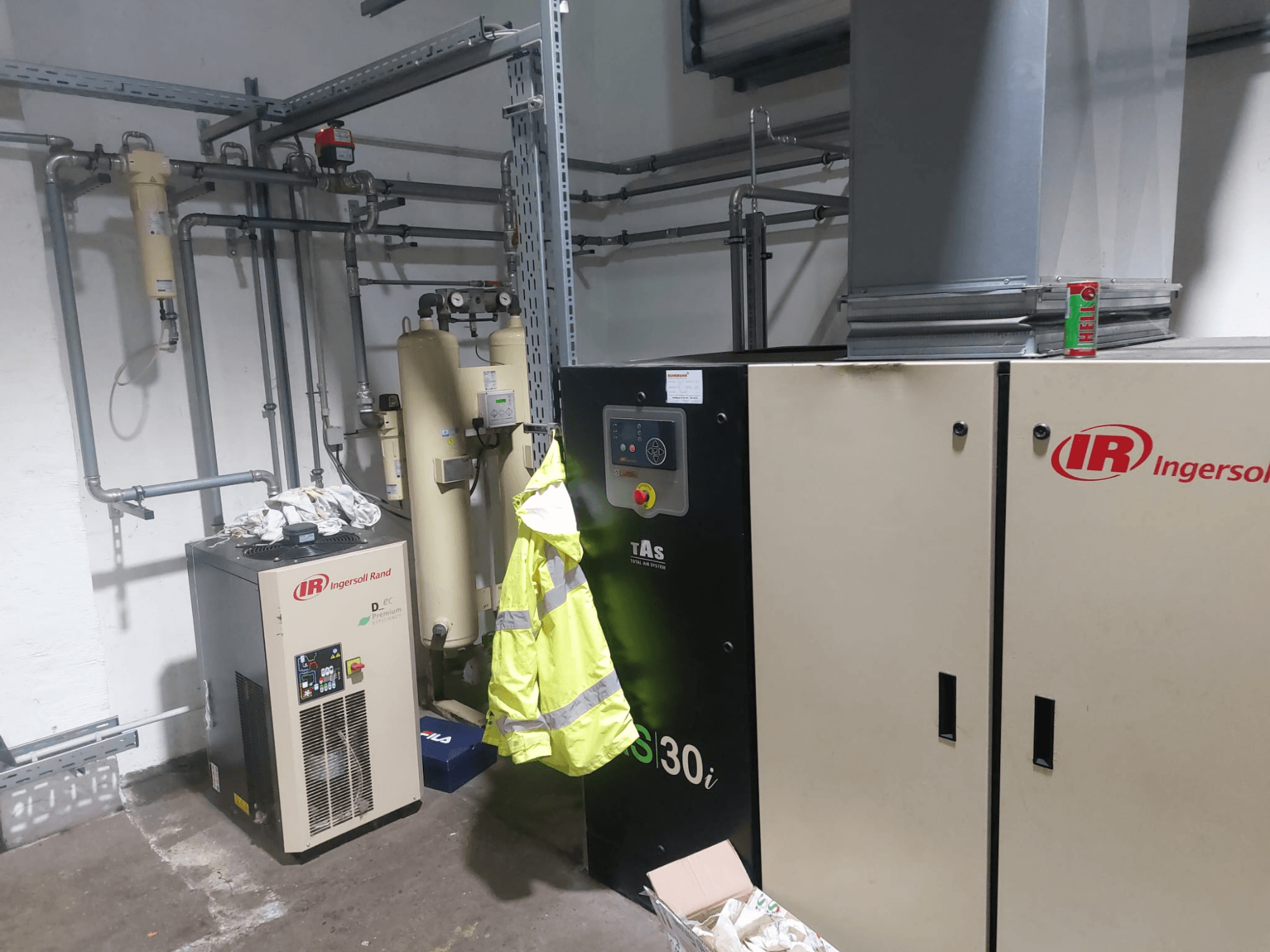 Bir atölyede bulunan Ingersoll Rand D480EC-A takım tezgahı; borular, kumanda panelleri ve yanında sarı bir güvenlik yeleği bulunan yandan görünüm.
