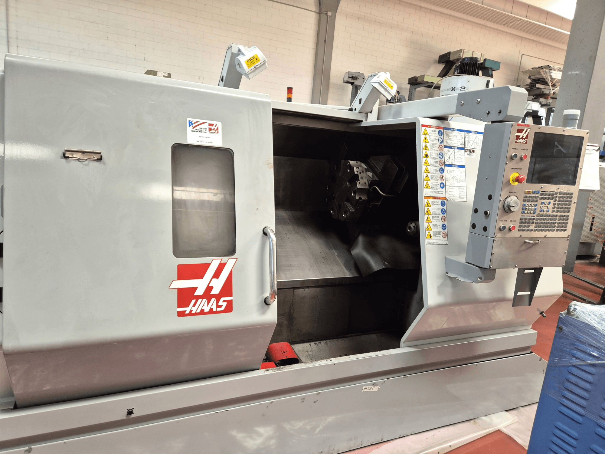 Haas SL 30TBHE yatay torna tezgahı; kontrol panellerini ve işleme işlemleri için açık bölmeyi gösteren önden görünüm.