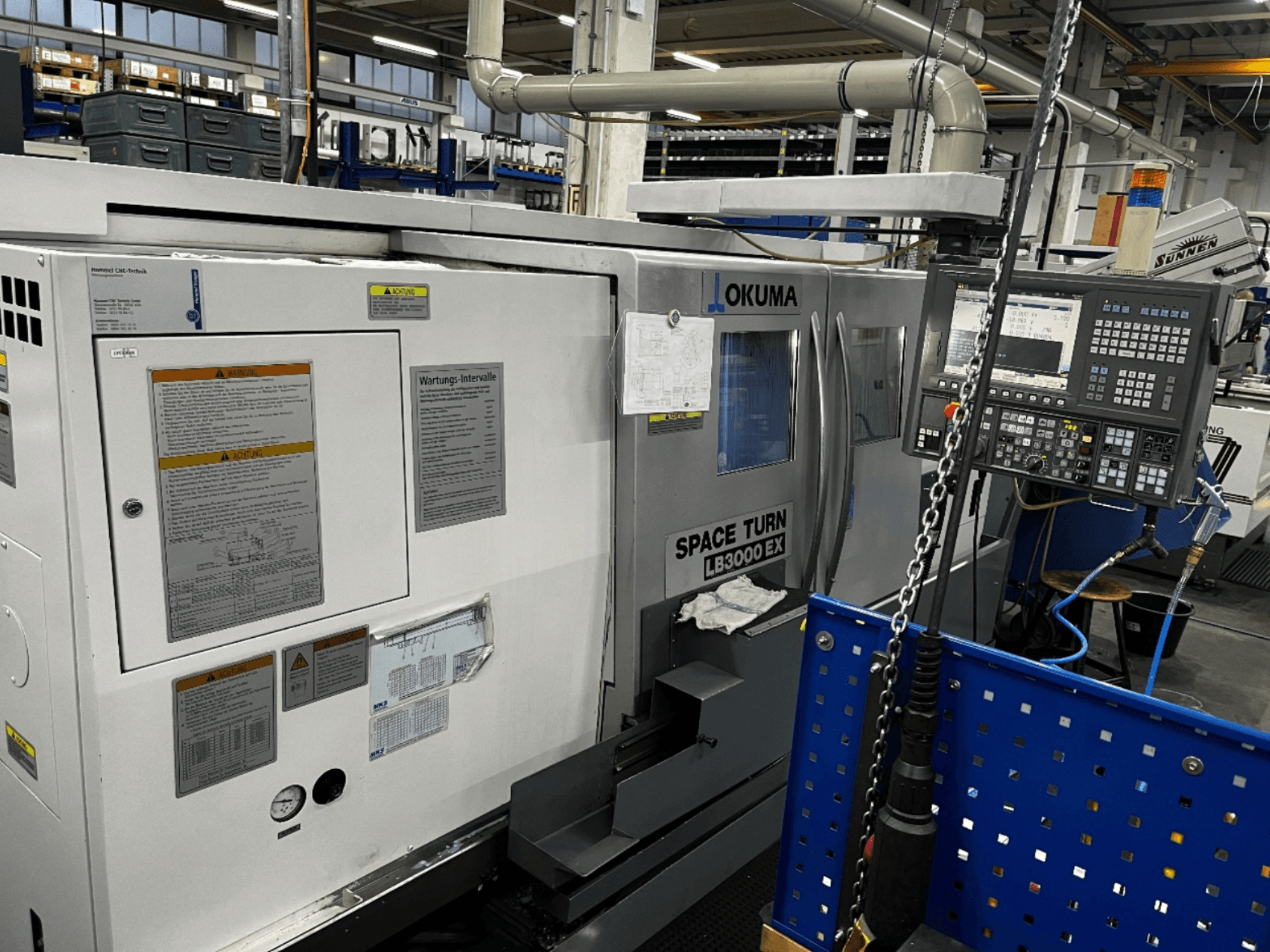 Okuma LB3000 EX yatay torna makinesi, önden görünüm, yan tarafta kontrol paneli ve güvenlik bilgileri.