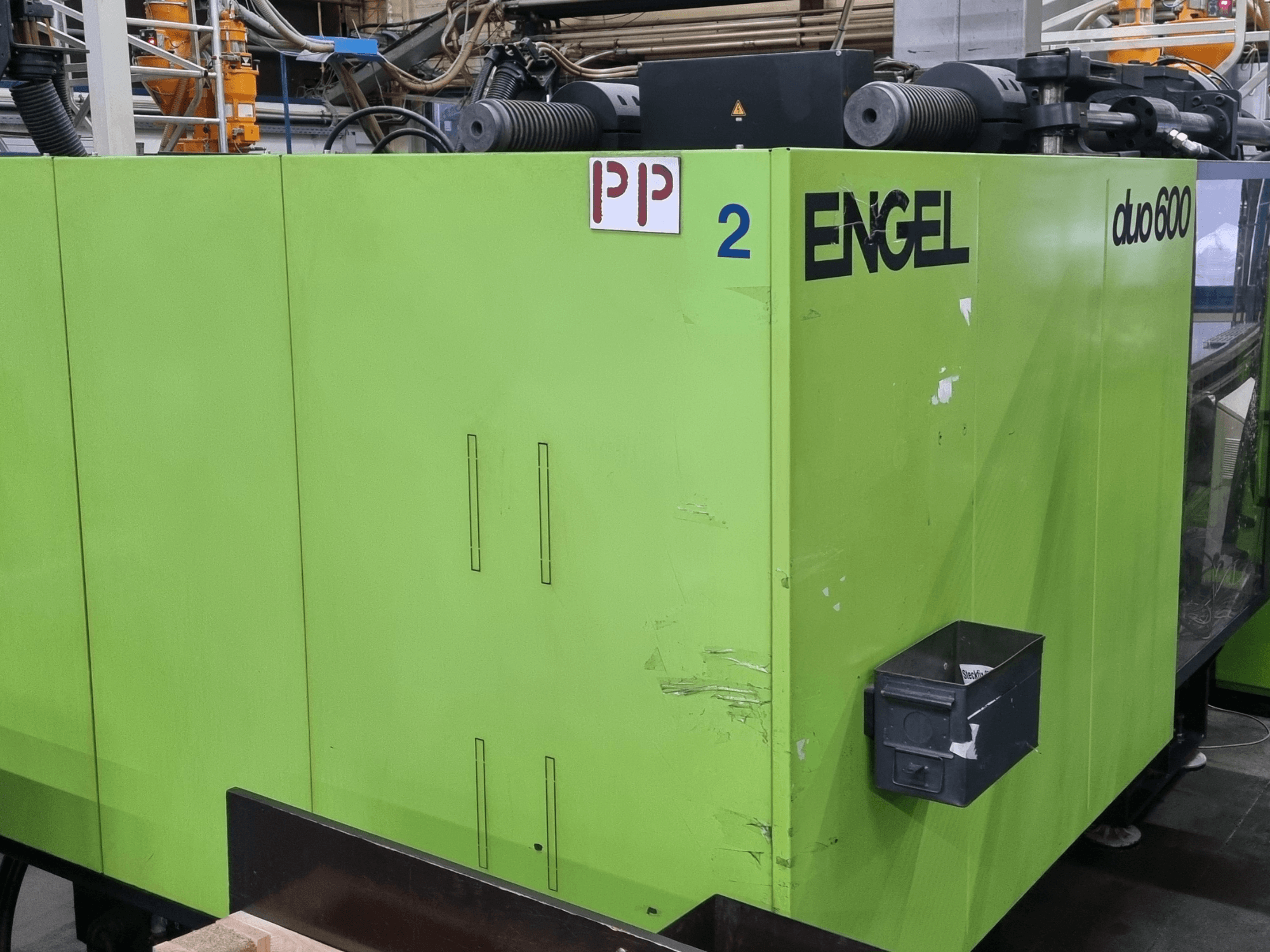 Engel duo 600 hidrolik enjeksiyon kalıplama makinesi, yeşil gövdeli, önden görünüm, etiketli parçalar ve malzeme saklama kutusu.