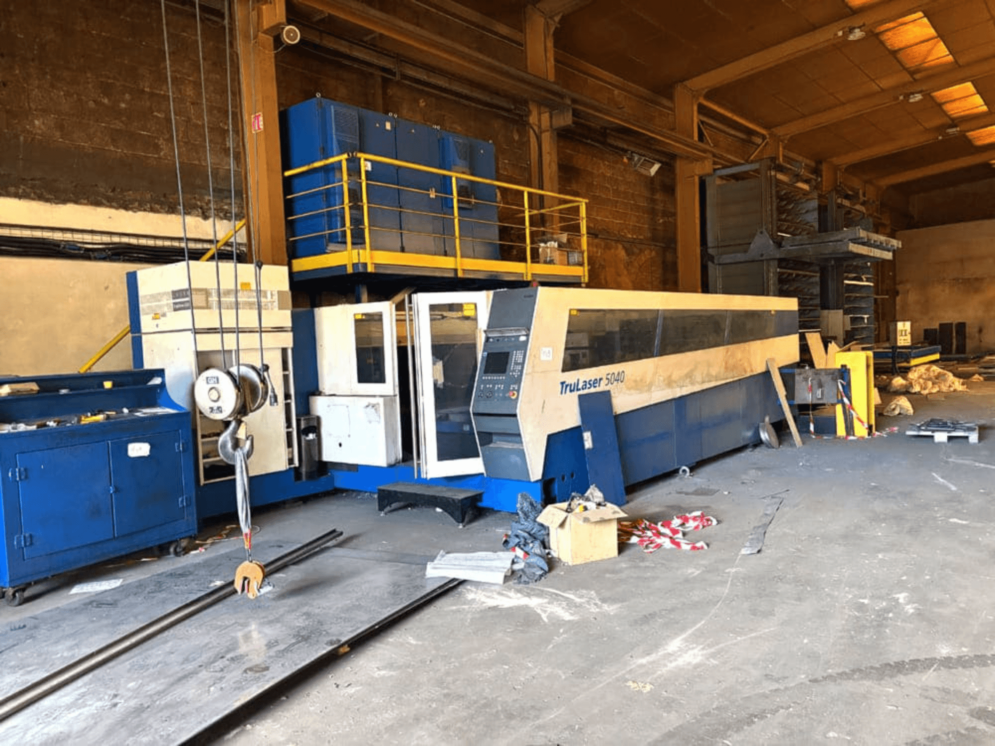 TRUMPF marka CO₂ lazer kesim makinesi, TRULASER 5040 modeli; bir atölyede, arka planı dağınık olan açılı önden görünüm.