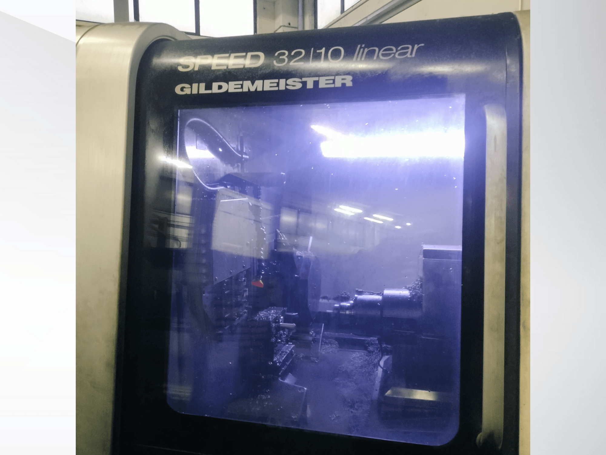 Gildemeister SPEED 3210 lineer CNC makinesinin önden görünümü, iç bileşenleri ve sıvı soğutucuyu çalışırken gösterir.
