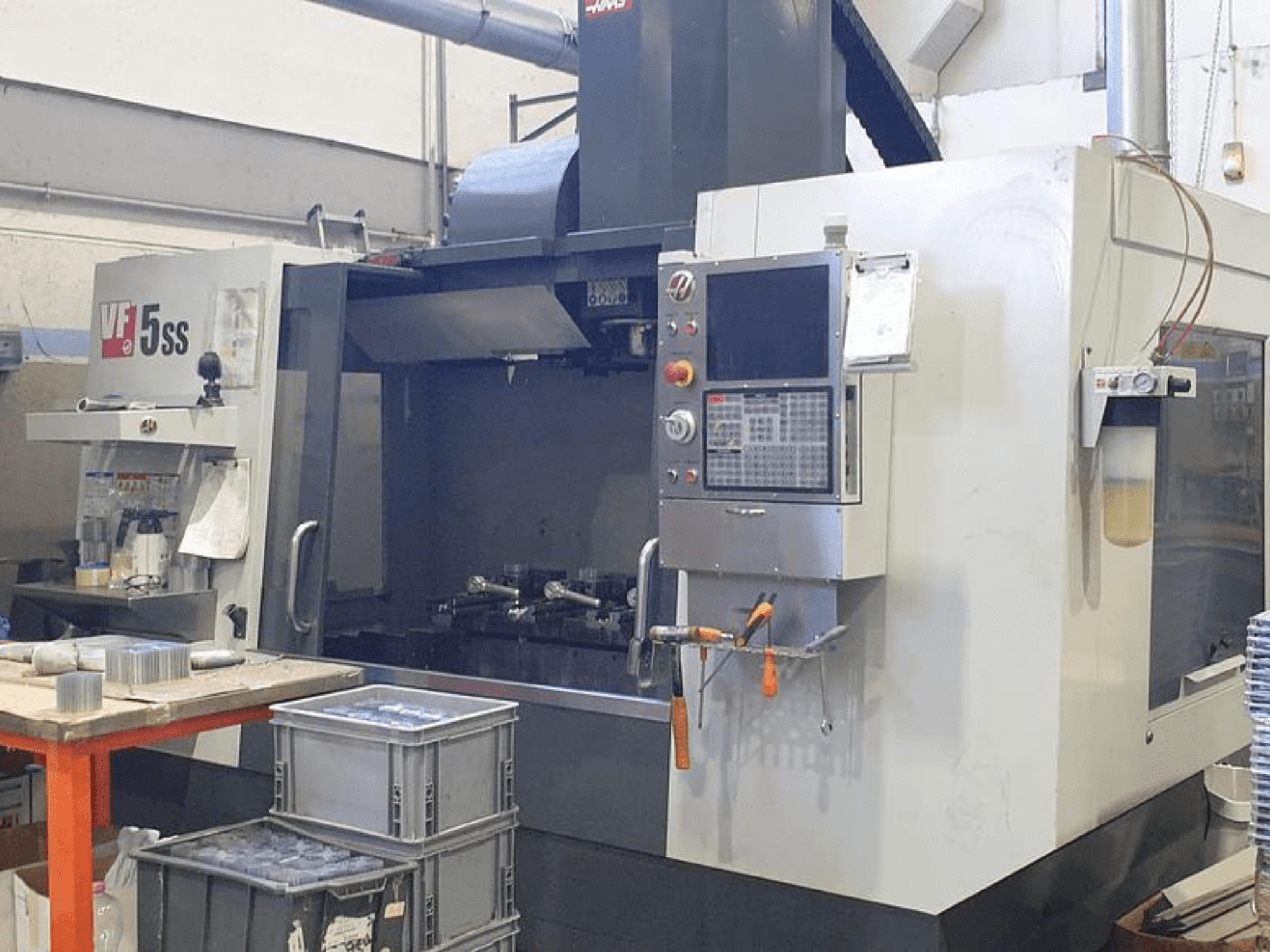 HAAS VF-5SS dikey işleme merkezinin önden görünümü, kontrol panelini, çalışma alanını ve saklama kutularını gösterir.