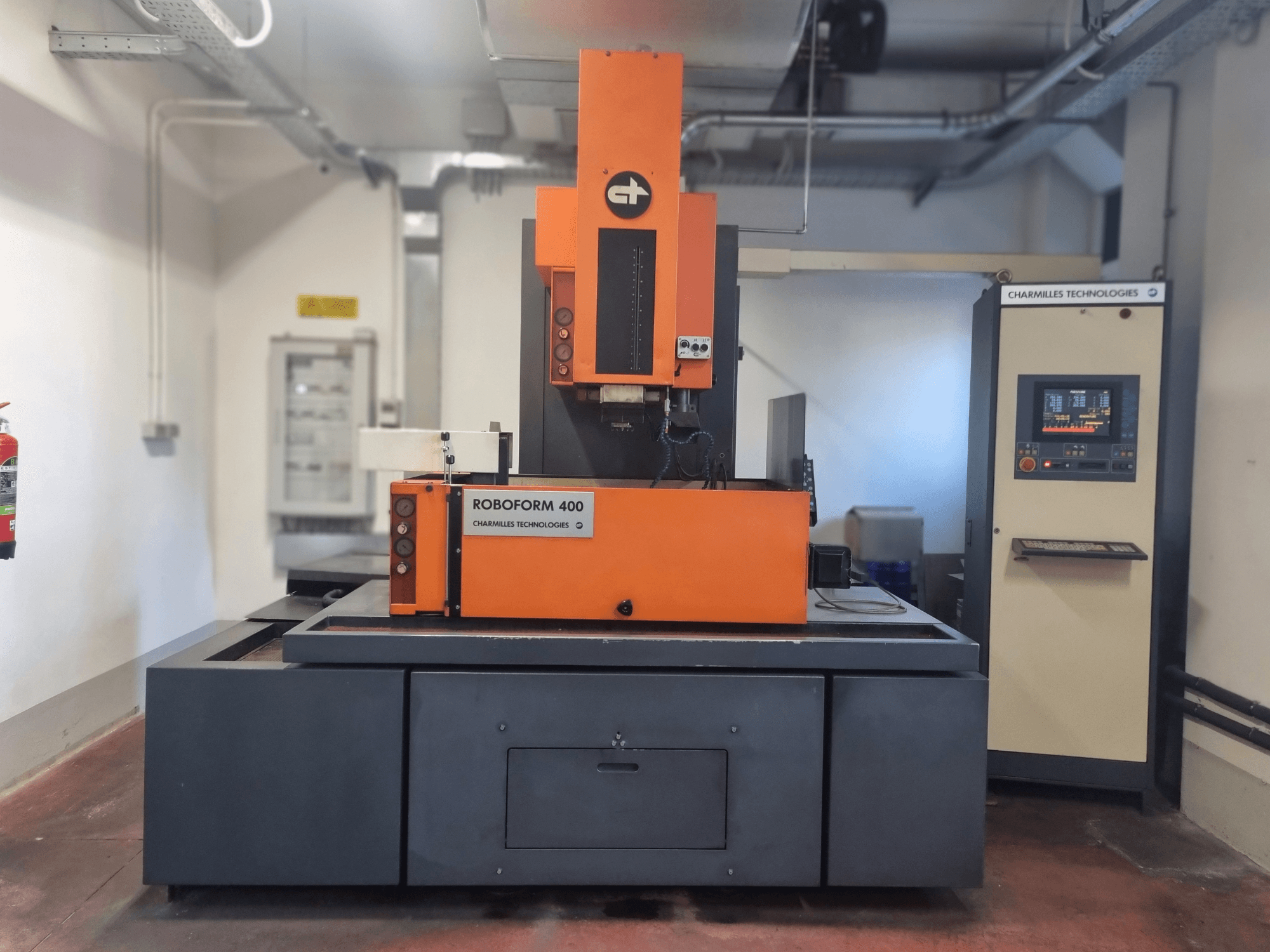 Charmilles Technologies'in Roboforn 400 makinesi, önden görünüm, turuncu ve gri bir tasarıma sahip, dijital kontrol paneli görünüyor.