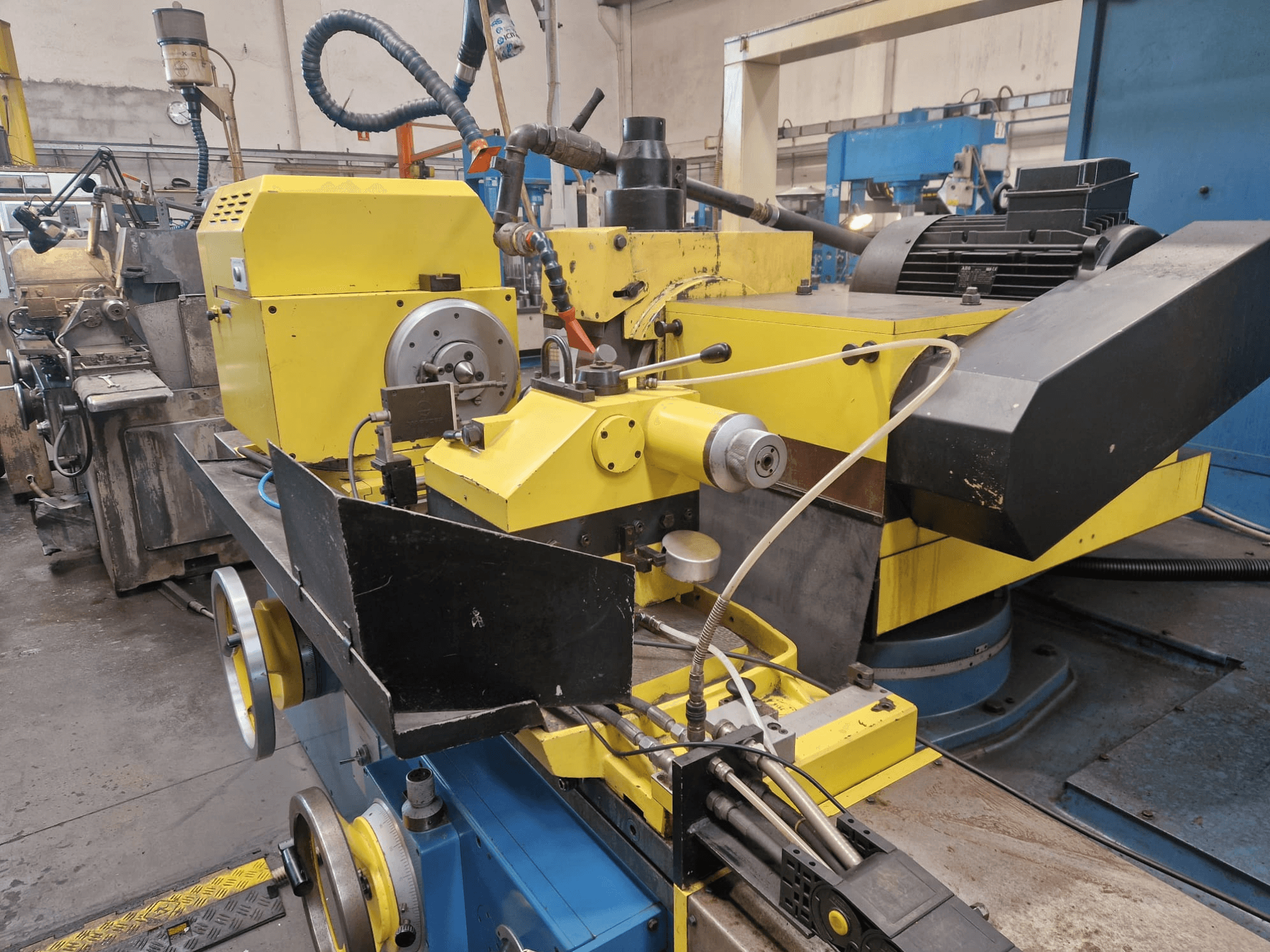 Kadran ve hortumlar içeren siyah bölümlü sarı endüstriyel makine, önden hafif bir açıyla görülüyor.