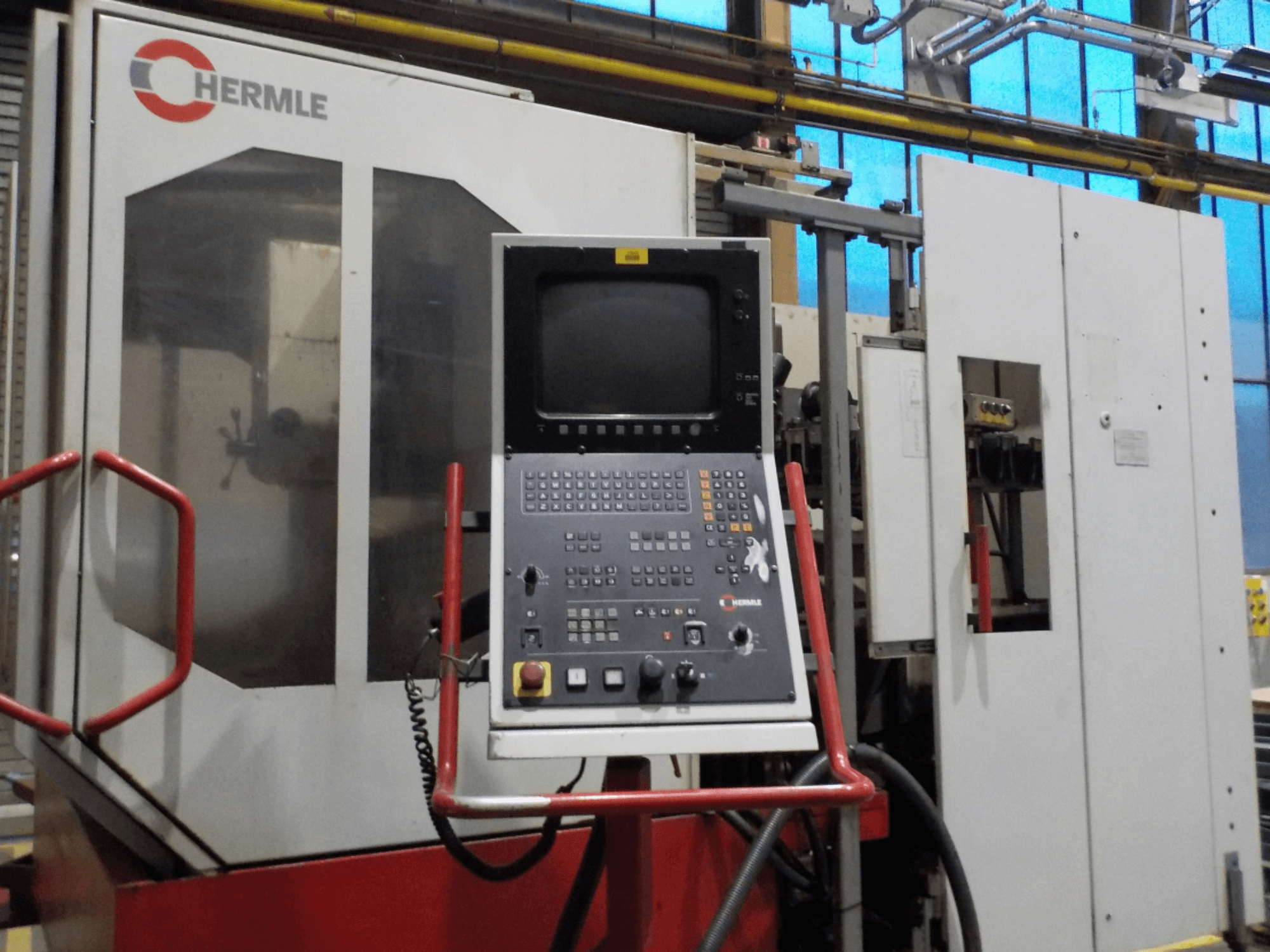 HERMLE UWF 1002 H dikey işleme merkezinin önden görünümü; düğmeler ve monitörün bulunduğu kontrol paneli görülmektedir.