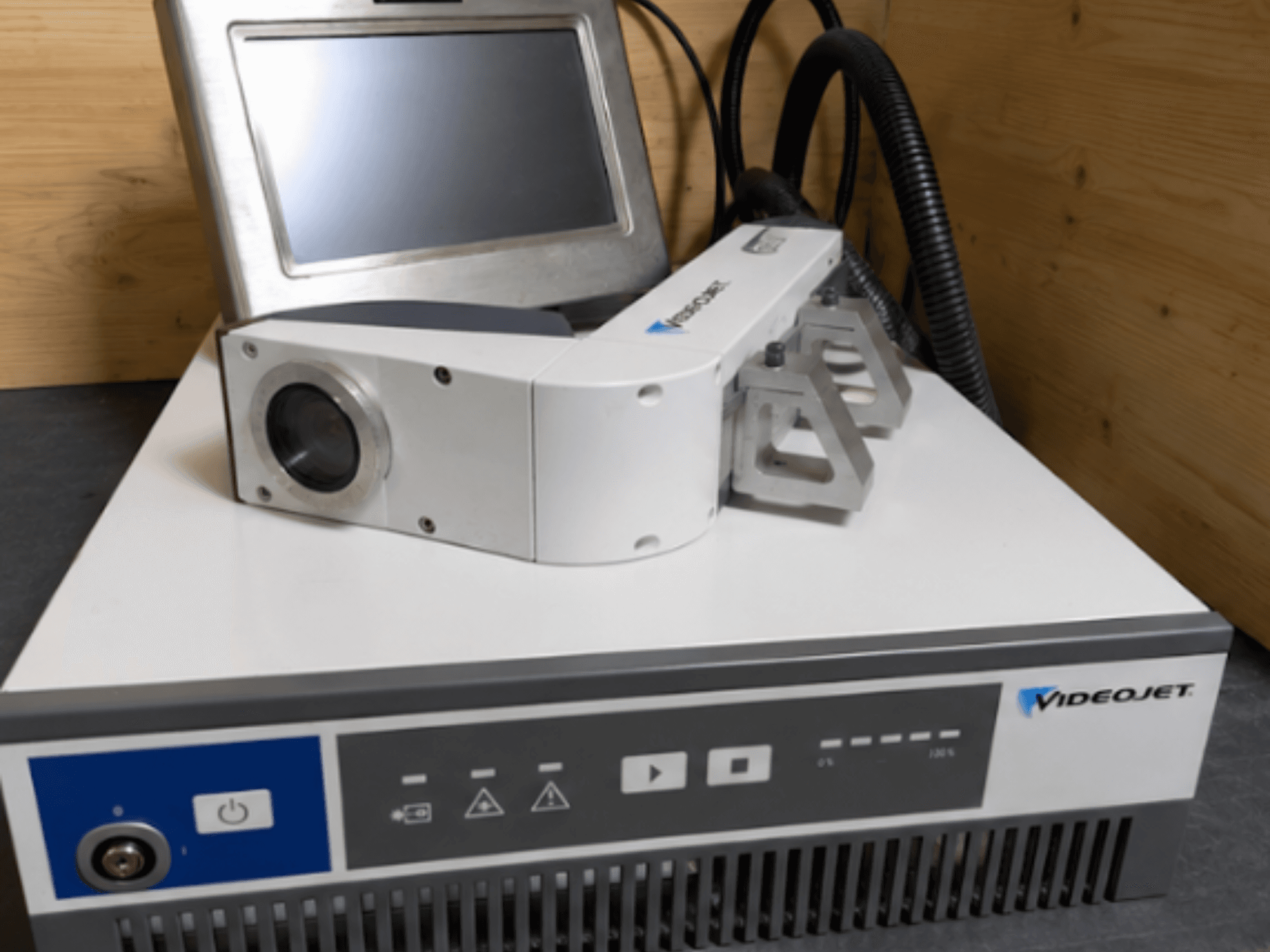 Videojet 7230 Lazer Gravür Makinesi, önden görünüm, kontrol panelini ve lensli ve eklentili lazer kafasını gösterir.