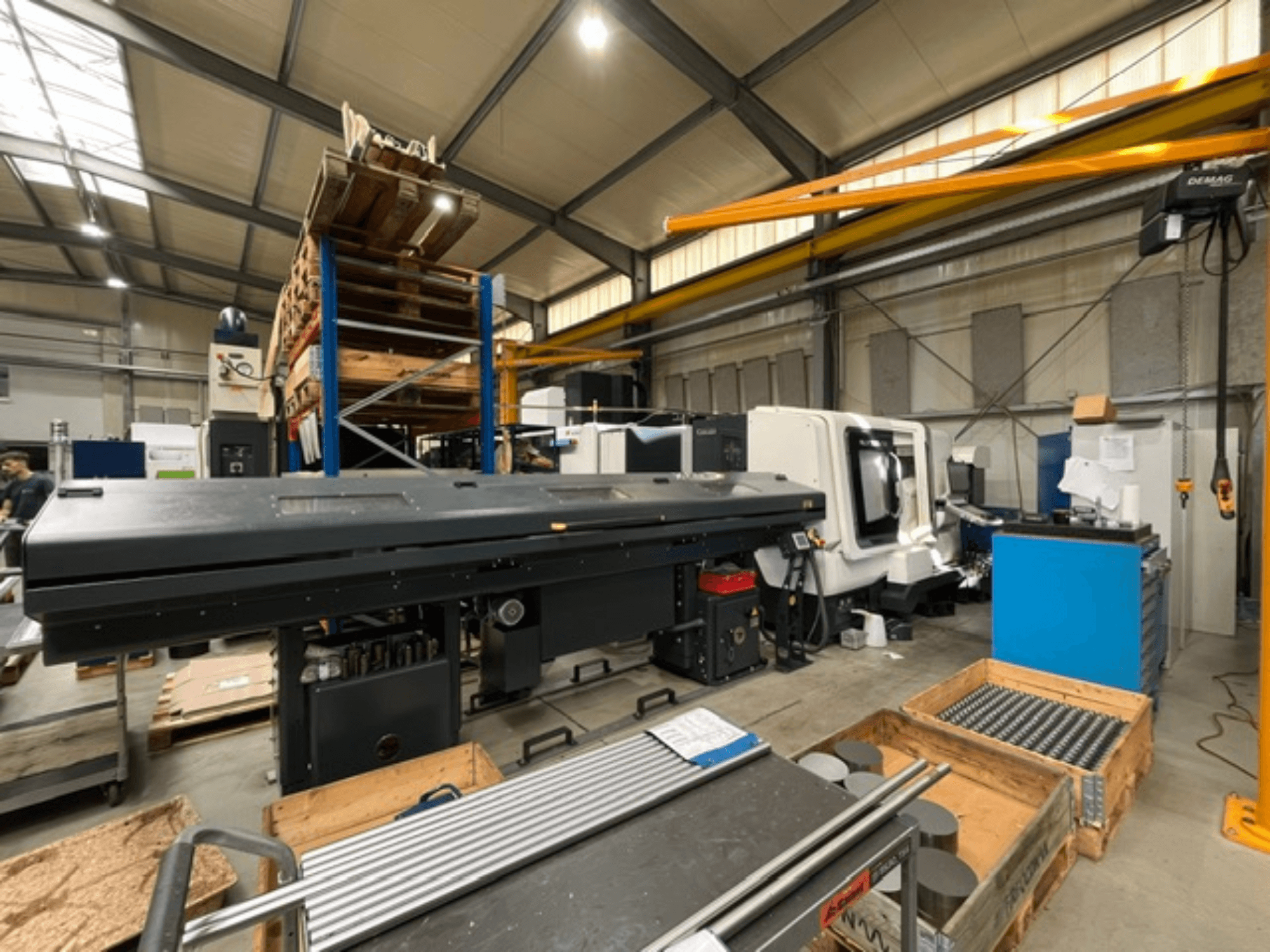 Fabrika ortamında bulunan, yandan bakıldığında takımları ve paletleri görülebilen bir DMG MORI MORI NLX 2500/700 SY yatay torna tezgahı.