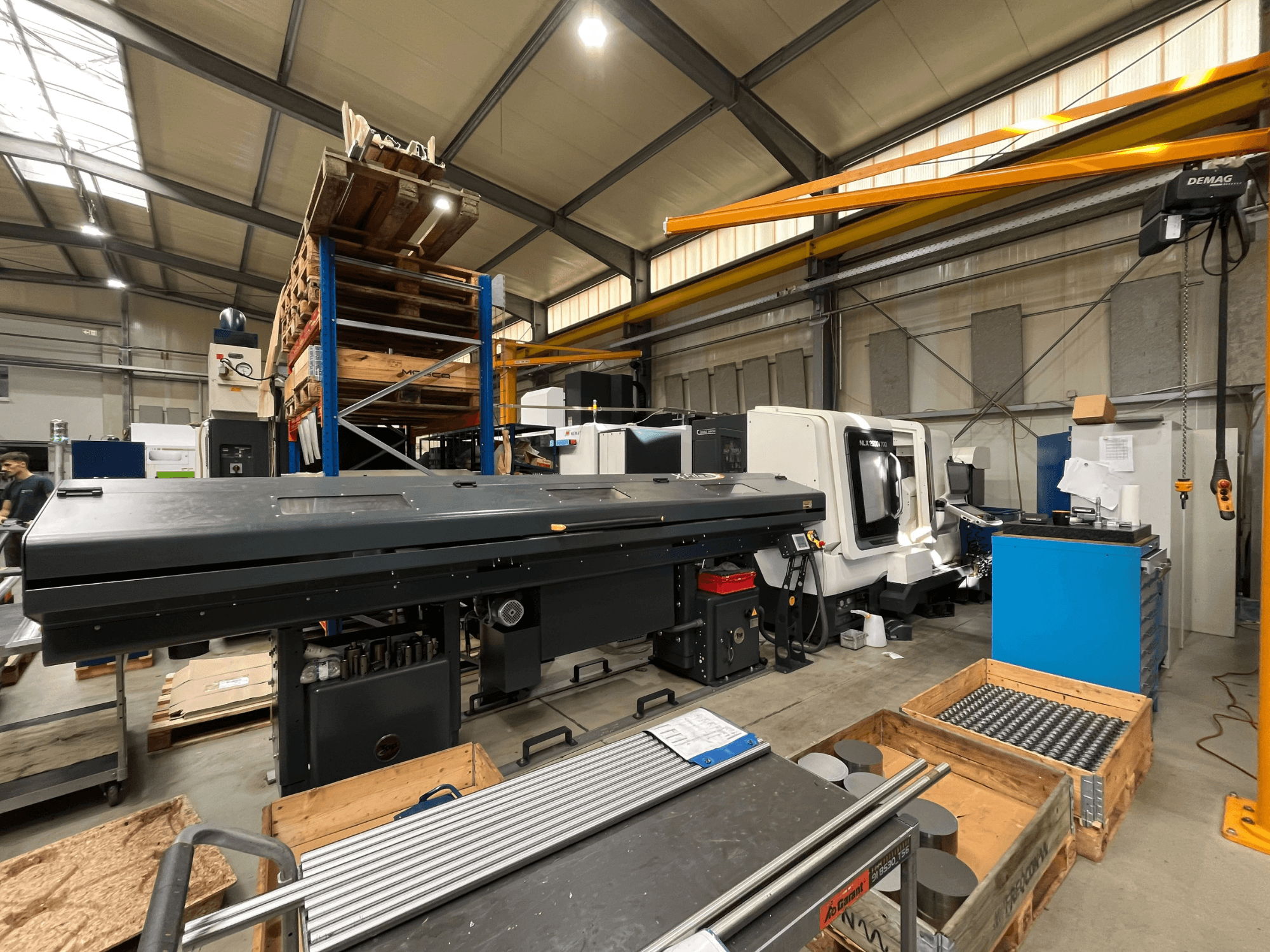 Bir atölyede bulunan DMG MORI MORI NLX 2500/700 SY yatay torna tezgahı; yan taraftan çekilmiş fotoğrafta arka planda depolama alanı ve aletler görülüyor.