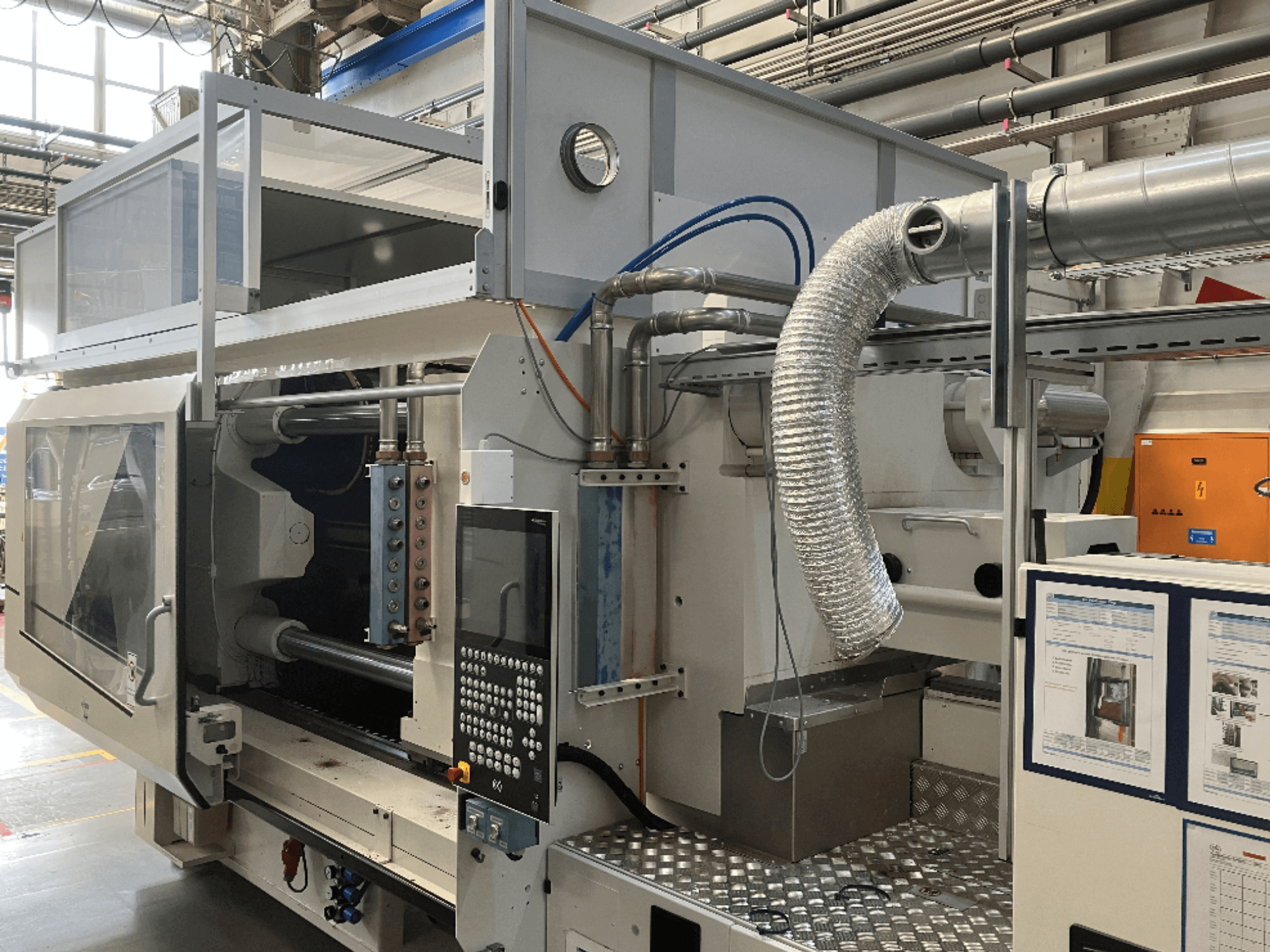 Brand X'ten endüstriyel makine, fabrika ortamında kontrol panelini, kanal sistemini ve makine bileşenlerini gösteren yandan görünüm.
