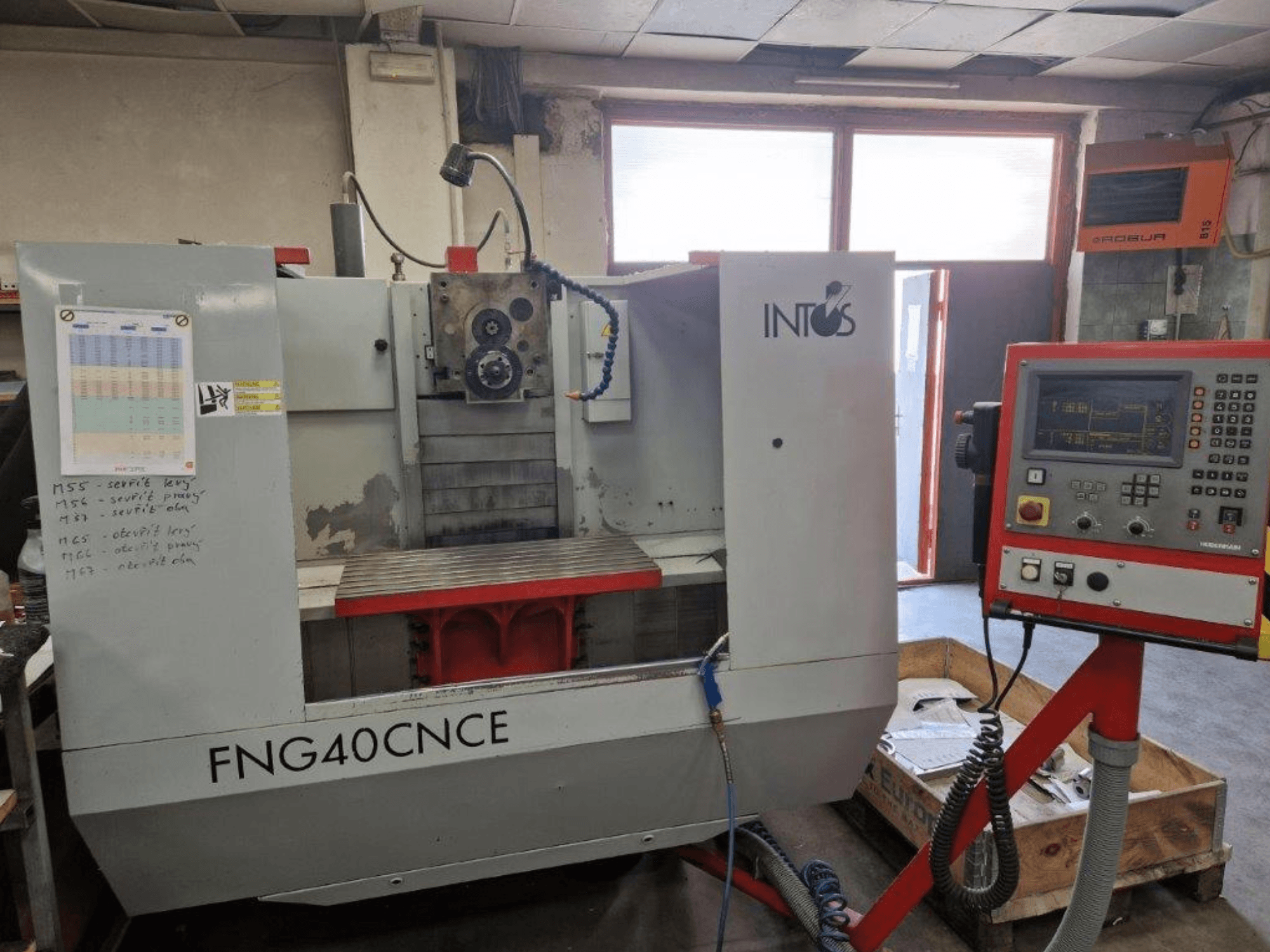 INTOS FNG40CNC makinesi, önden görünüm, kontrol paneli, operasyonel parçalar ve metal bir çalışma tablası içerir. İşleme için idealdir.