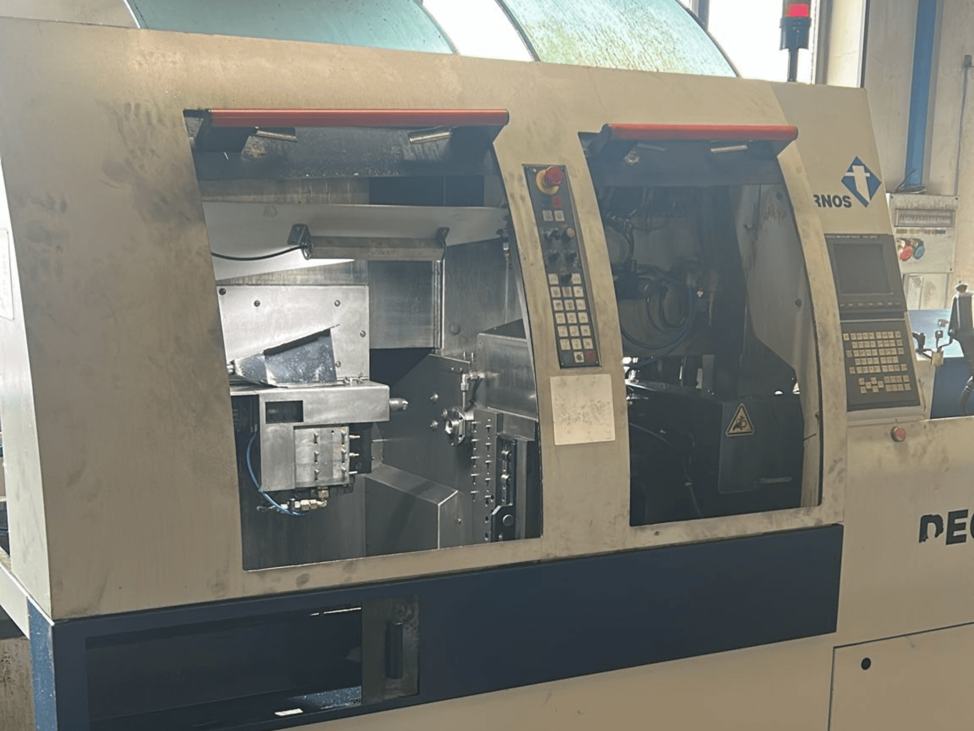 Alt metin: TORNOS Deco 13 b İsviçre Tipi Torna Tezgahının önden görünümü, kontrol panelleri ve iç bileşenleri görülebilir.