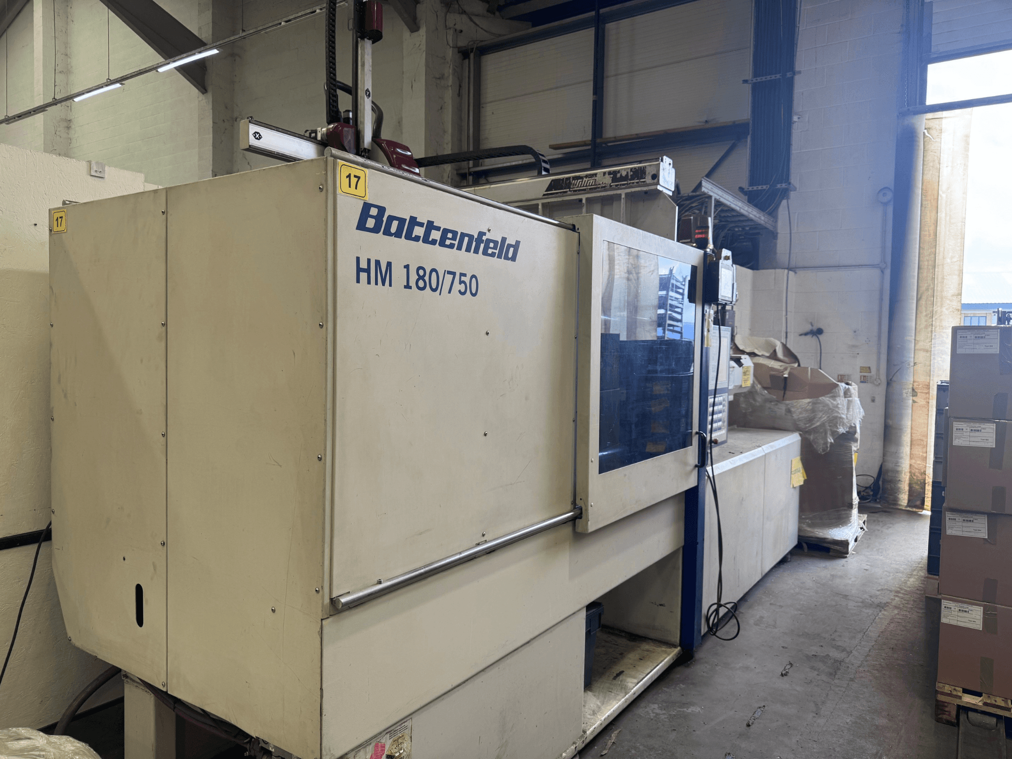 Battenfeld HM150750 hidrolik enjeksiyon kalıplama makinesinin önden görünümü, kontrol panelini ve çevresindeki kurulumu sergiliyor.