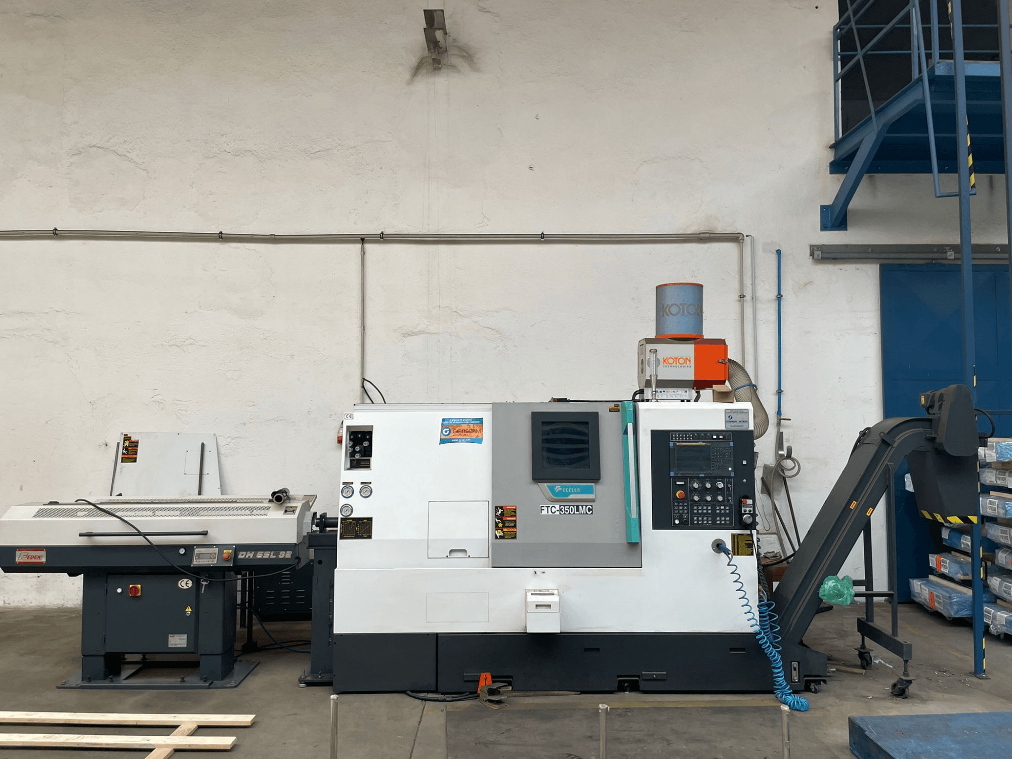 Bir atölyede Feeler FTC 350 LMC yatay tornalama makinesi, kontrol paneli ve takım besleme hatları sergileniyor. Yandan görünüm.
