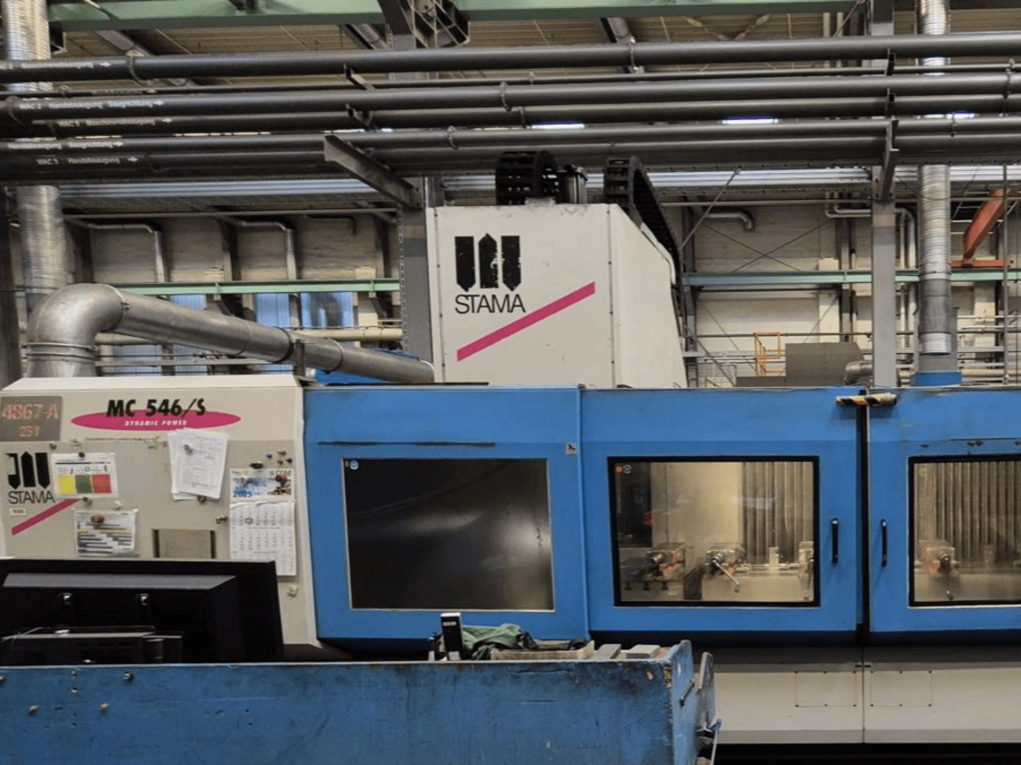 STAMA MC 546/S dikey işleme merkezinin önden görünümü, kontrol paneli ve görünür takımlarla işleme alanı.