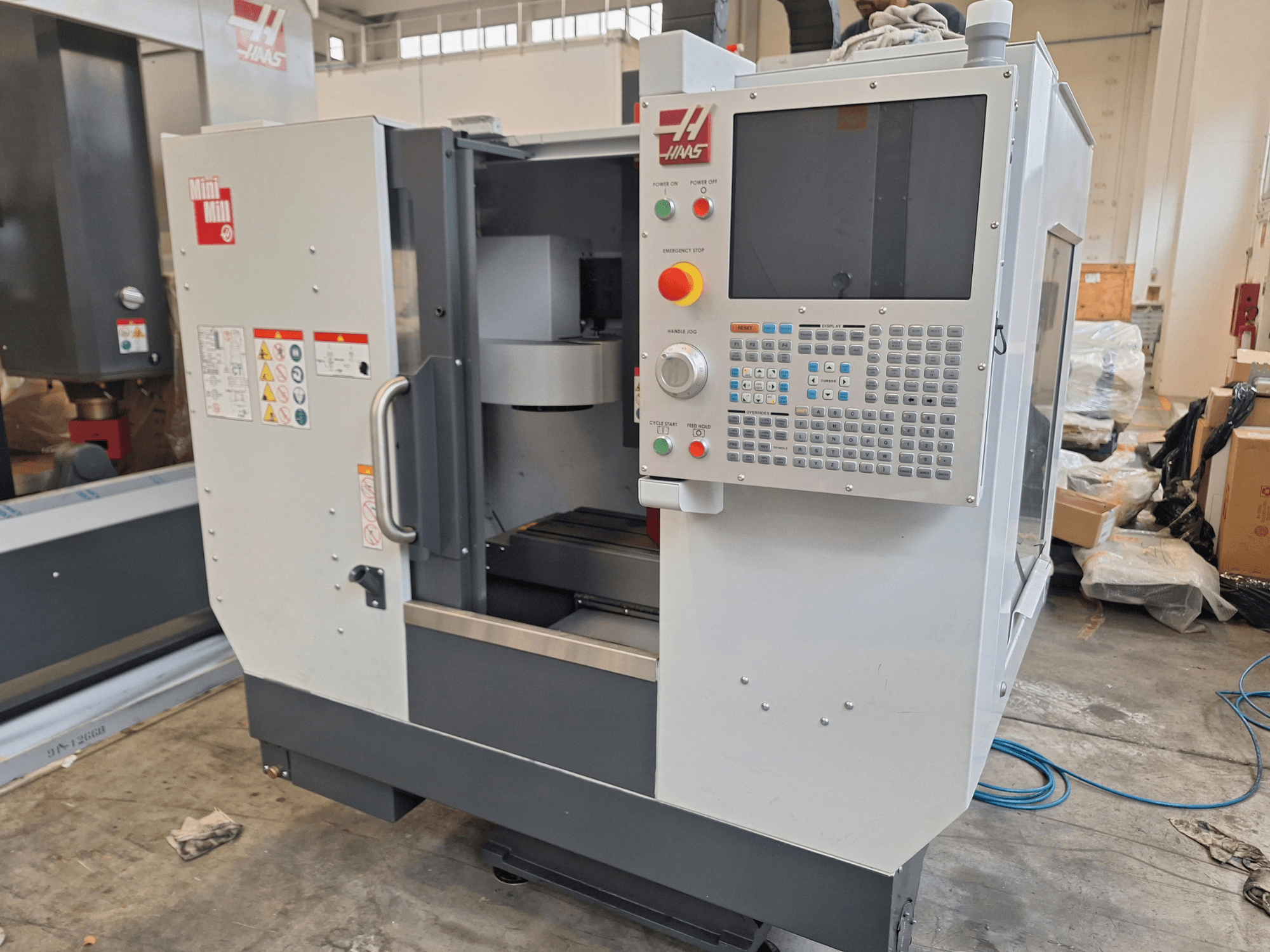 HAAS Mini Mill dikey işleme merkezinin önden görünümü; düğmeler ve bir ekran içeren kontrol paneli ile birlikte.