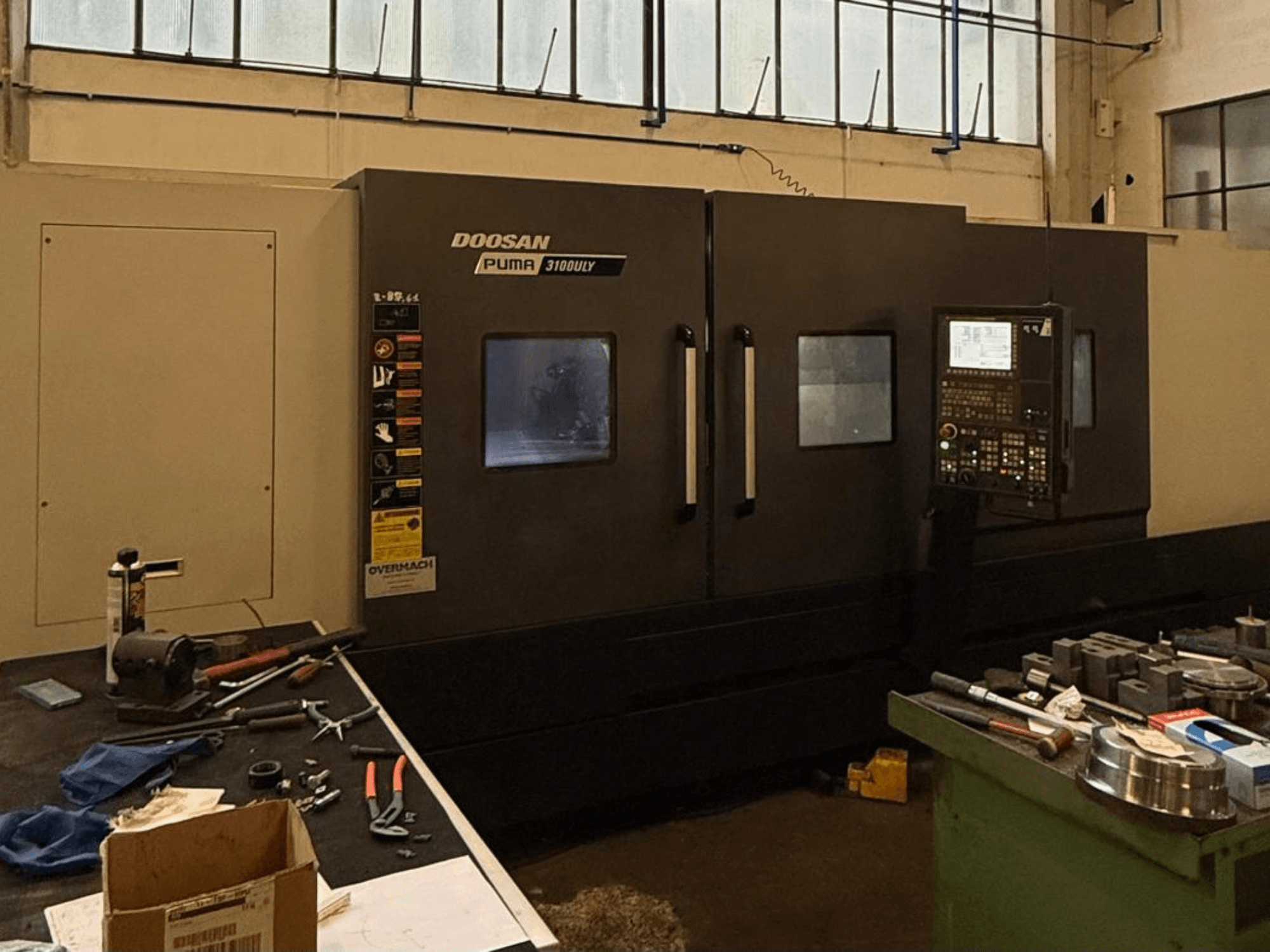 Atölyede Doosan Puma 3100LY CNC torna tezgahı, yandan görünüm, kontrol paneli ve aletler tezgah üzerinde görülebilir.