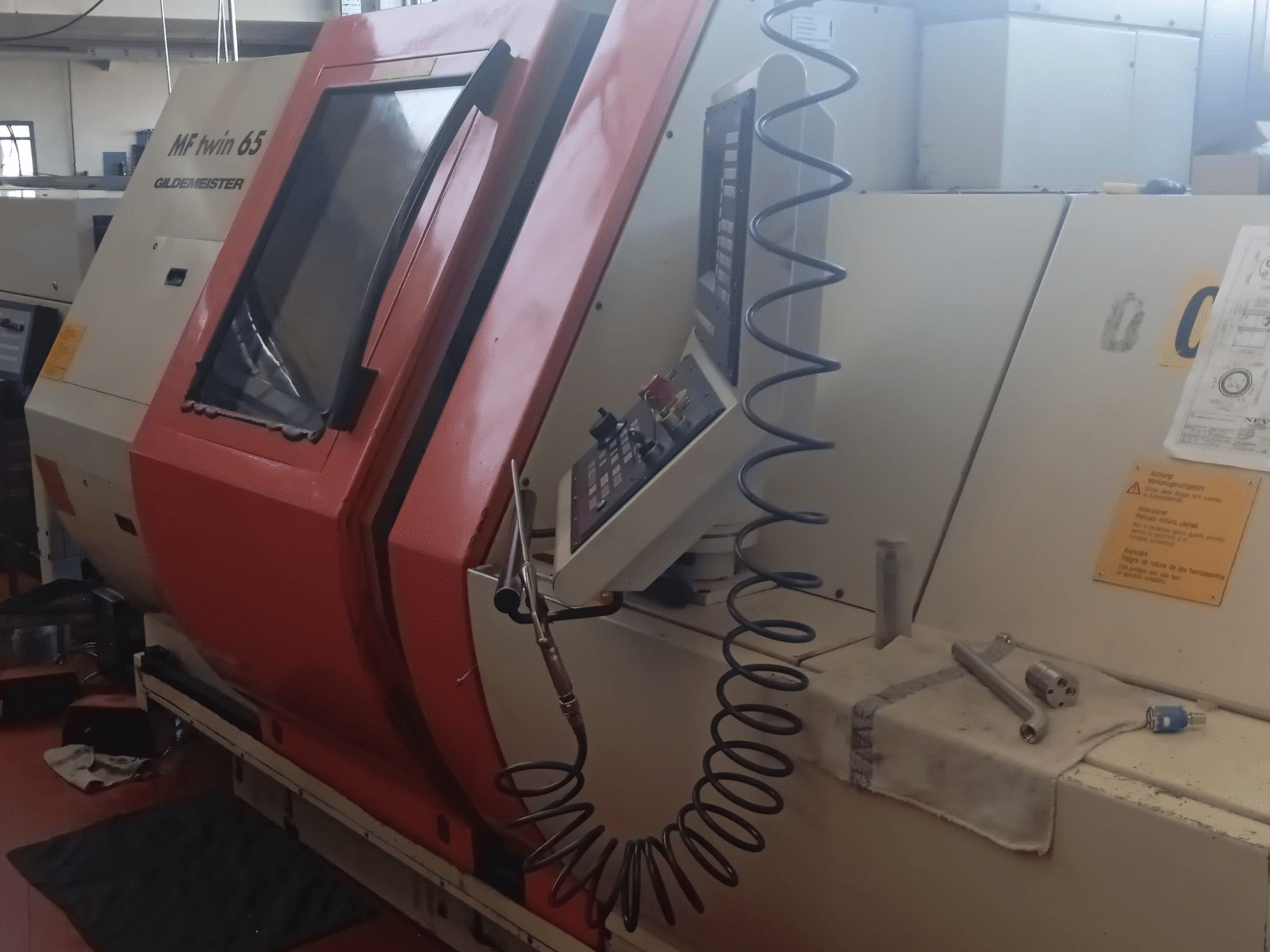 Turuncu ve beyaz MF twin 65 Gliedemeister makine, önden görünüm, kontrol paneli ve bir bez üzerinde aletler.