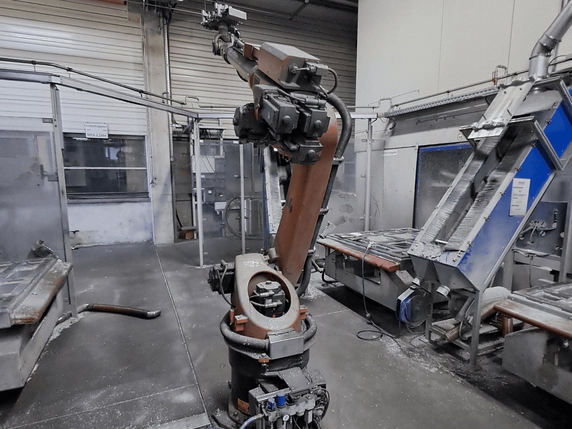 Bir atölye ortamında bulunan KUKA KR 30L16-2 robot kolu, önden görünüm; arka planda toz ve makine parçaları görülüyor.