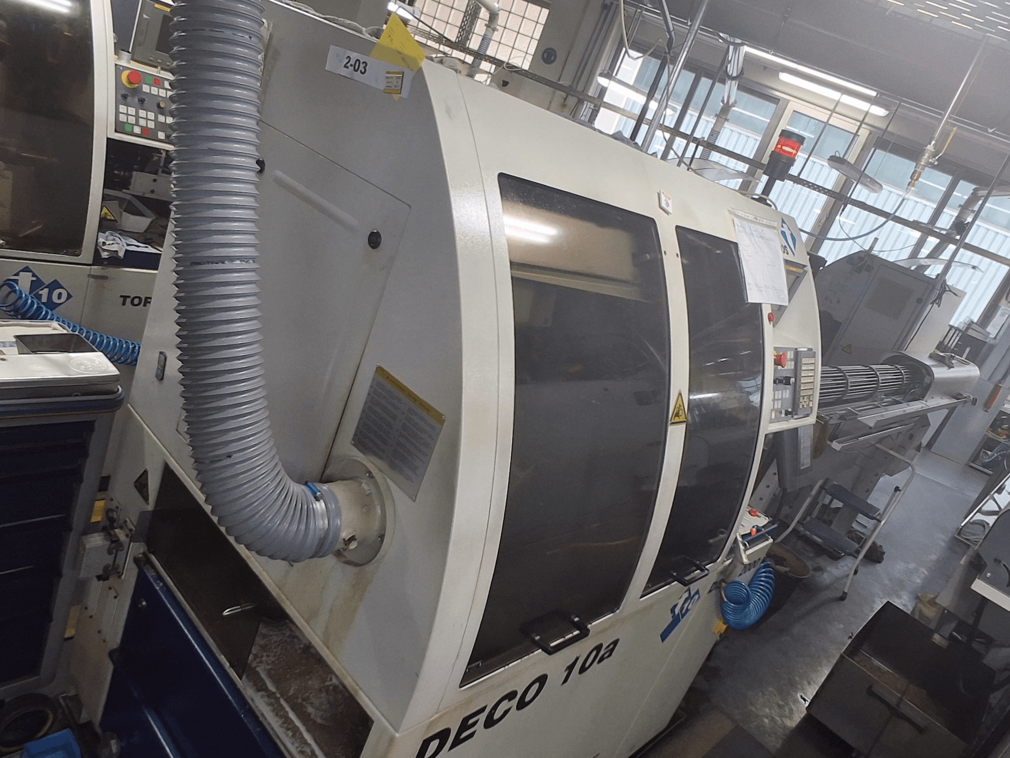 DECO 10a makinenin önden görünümü; büyük bir kontrol paneli, kanallar ve çalışma etiketleri görülebilir.