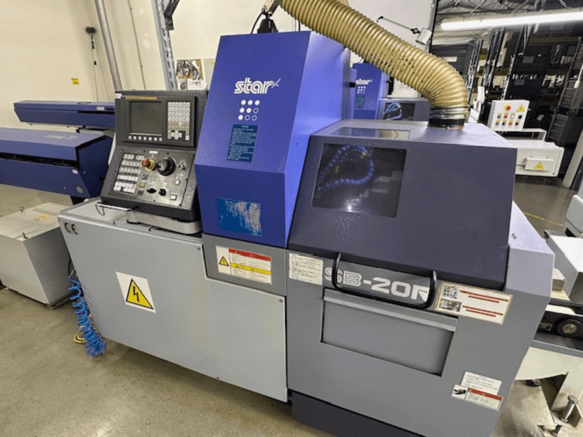 Star SB-20R tip N İsviçre tipi torna makinesi, önden görünüm, kontrol paneli, emme hortumu ve görünür tehlike sembolleri.